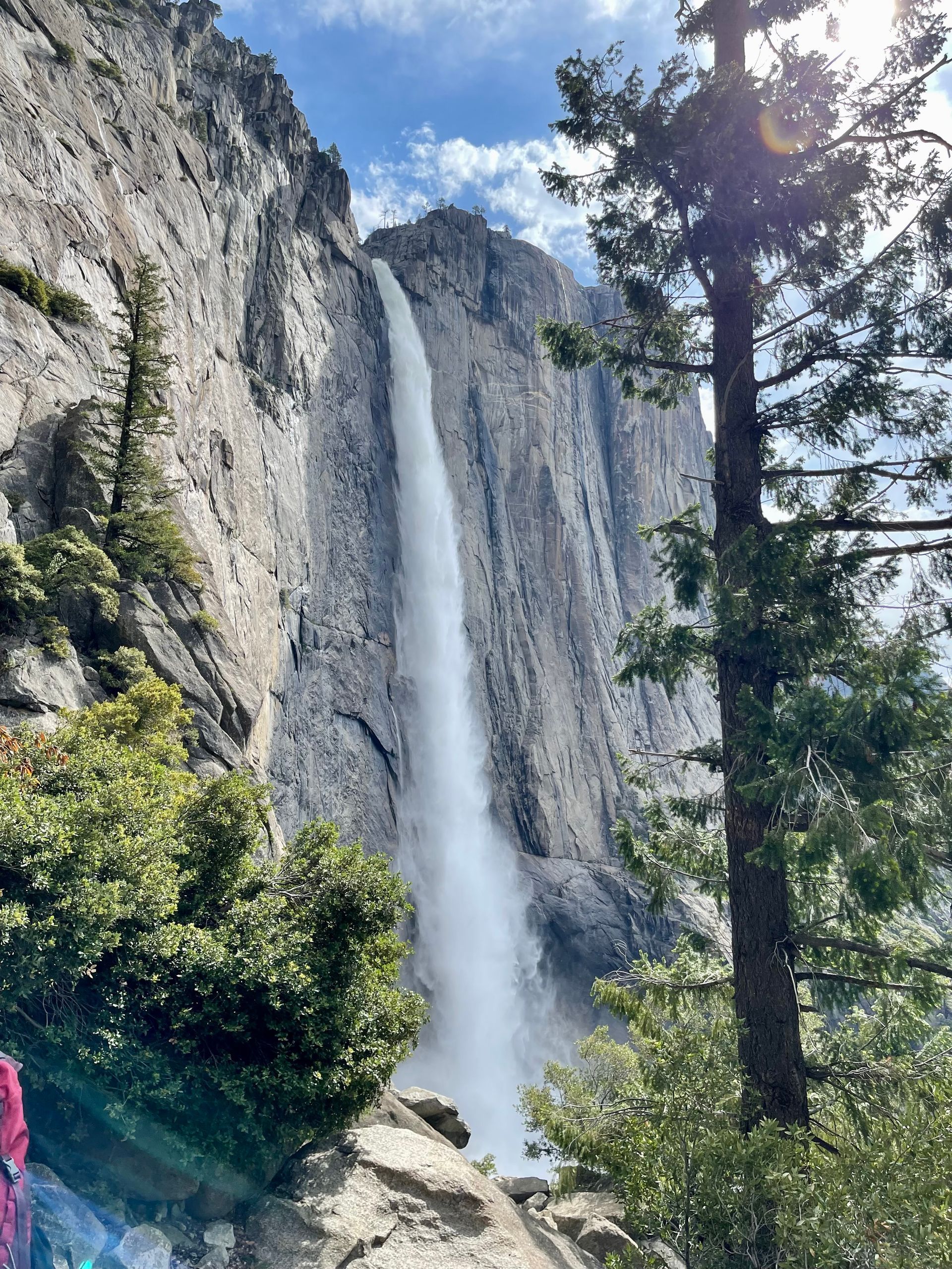 A waterfall is coming down the side of a mountain surrounded by trees.