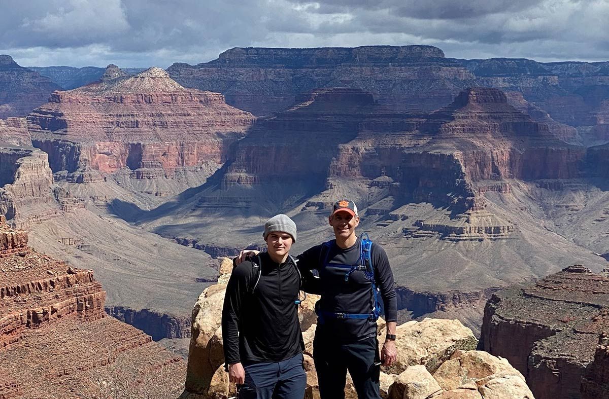 Two people pose in front of a majestic canyon