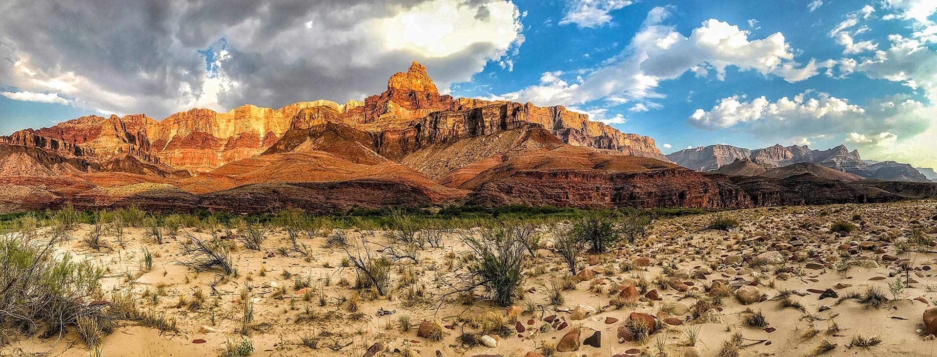 A desert landscape with mountains in the background and a cloudy sky.