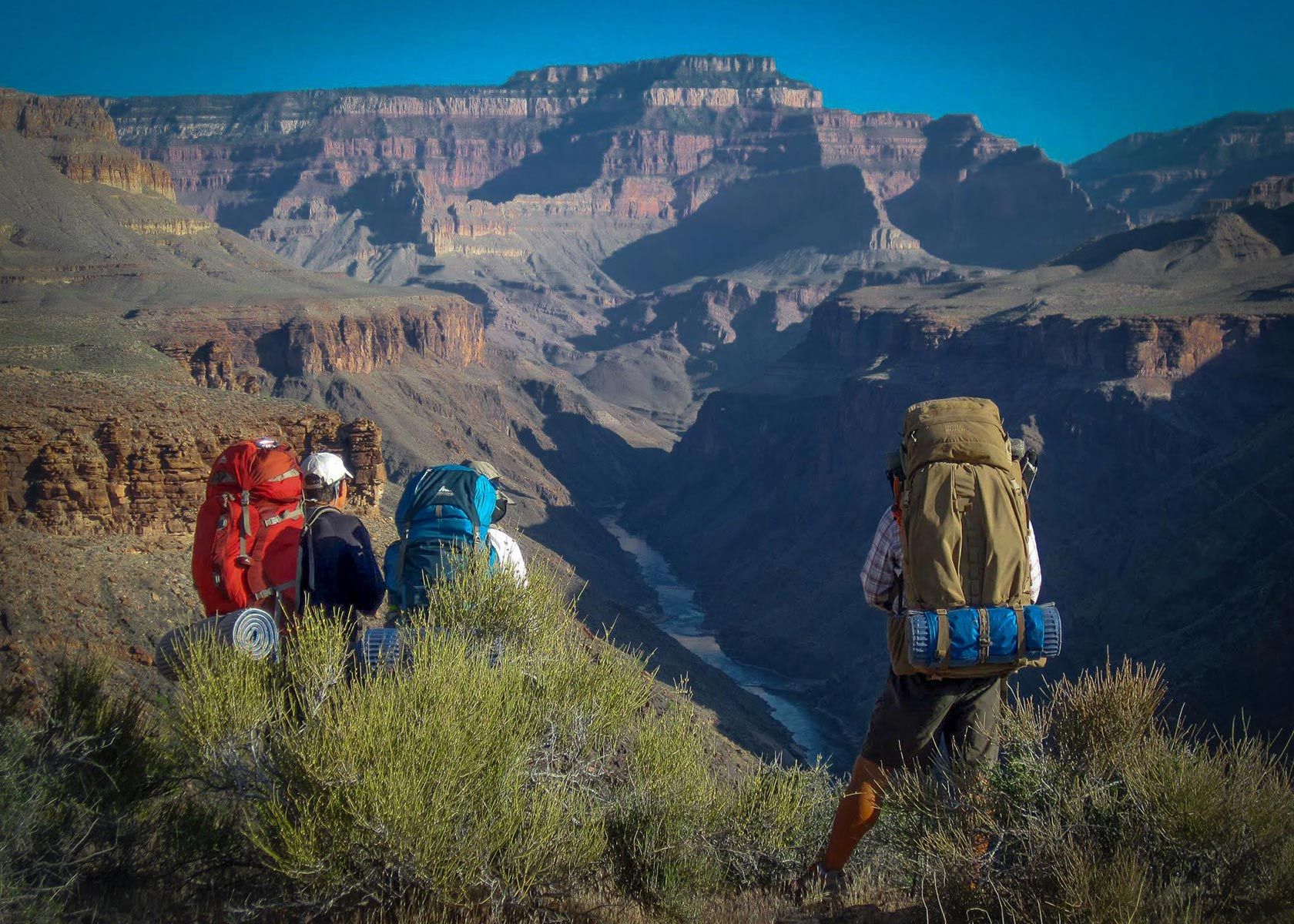 A group of people with backpacks standing on top of a mountain.