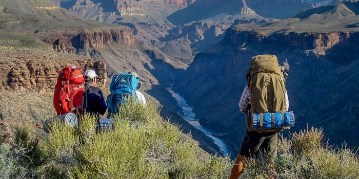 A group of people with backpacks are hiking up a mountain.