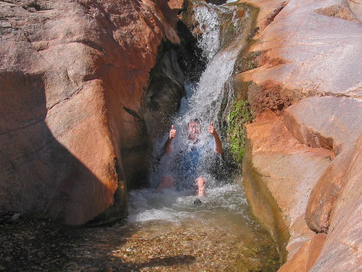 A person is standing in a waterfall surrounded by rocks.