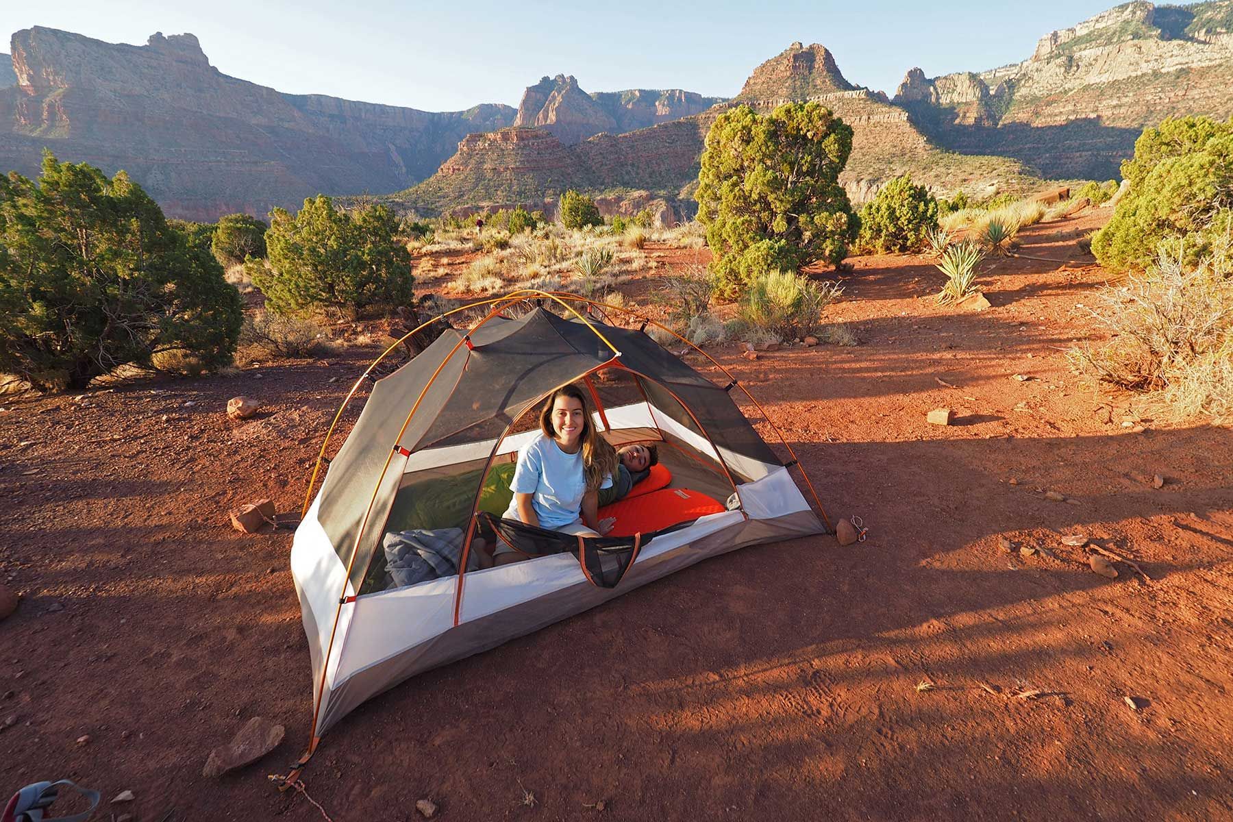 A man and woman are sitting in a tent in the desert