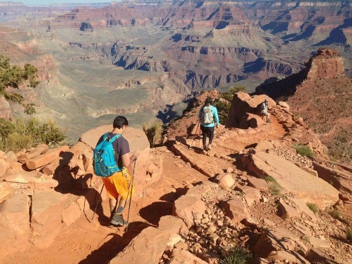 A man and a woman are hiking on a rocky trail