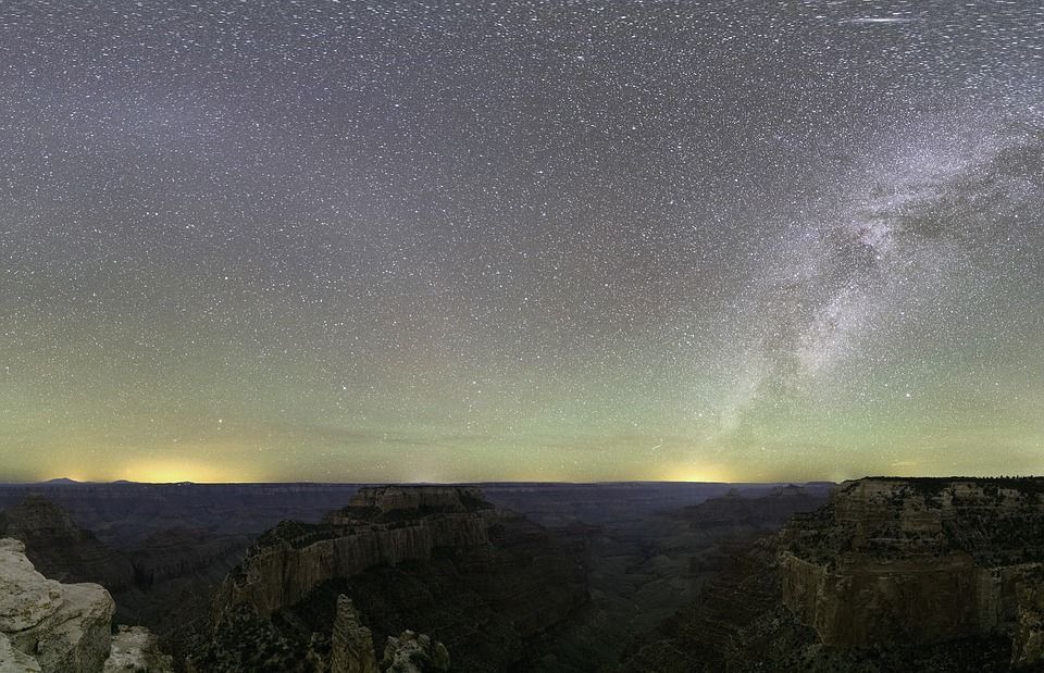 A night sky filled with lots of stars over a canyon.