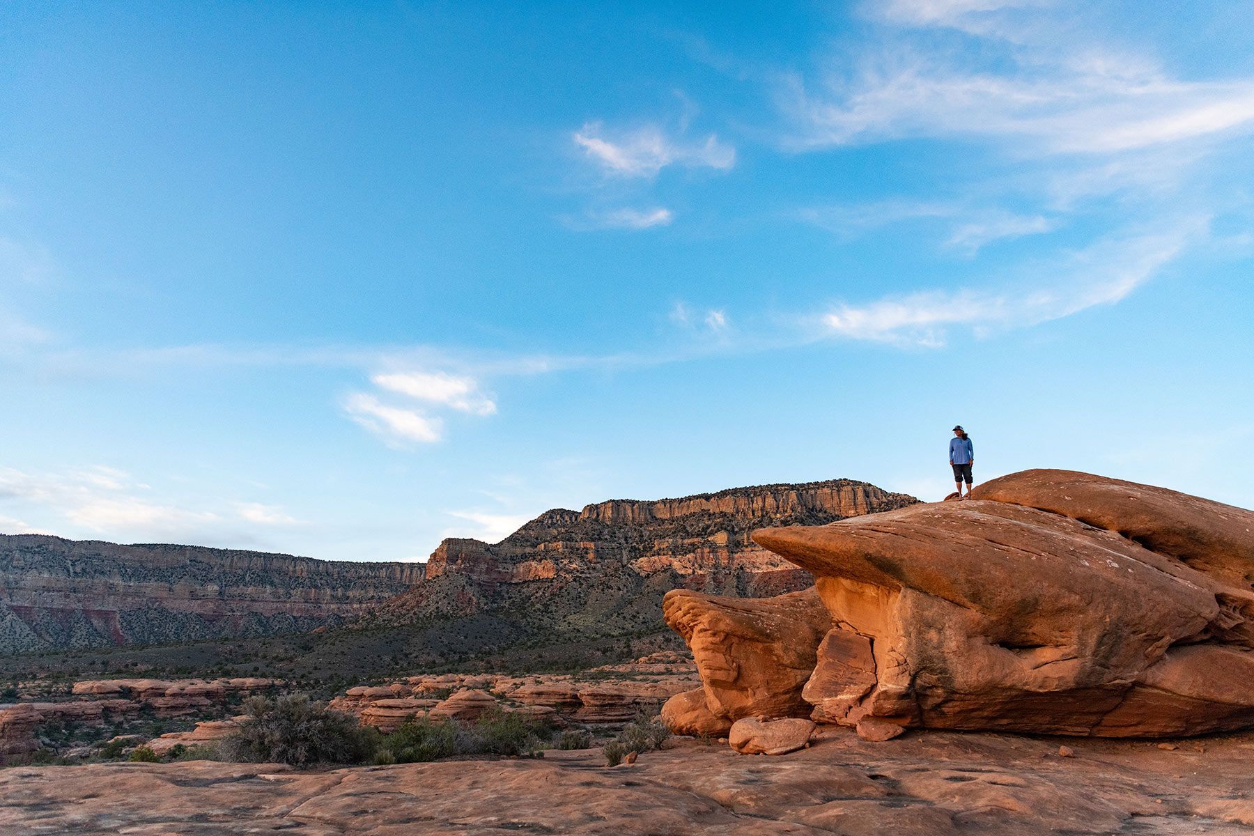 A man is standing on top of a rock formation in the desert.