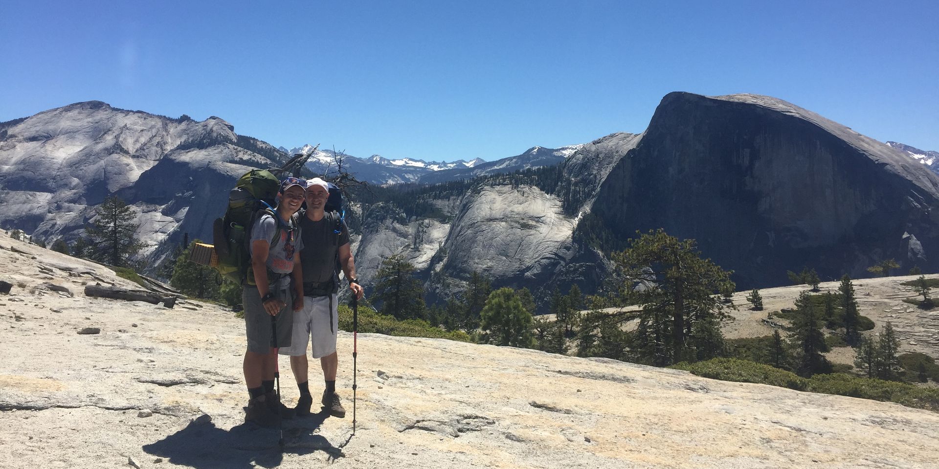 A couple of people standing next to each other on top of a mountain.