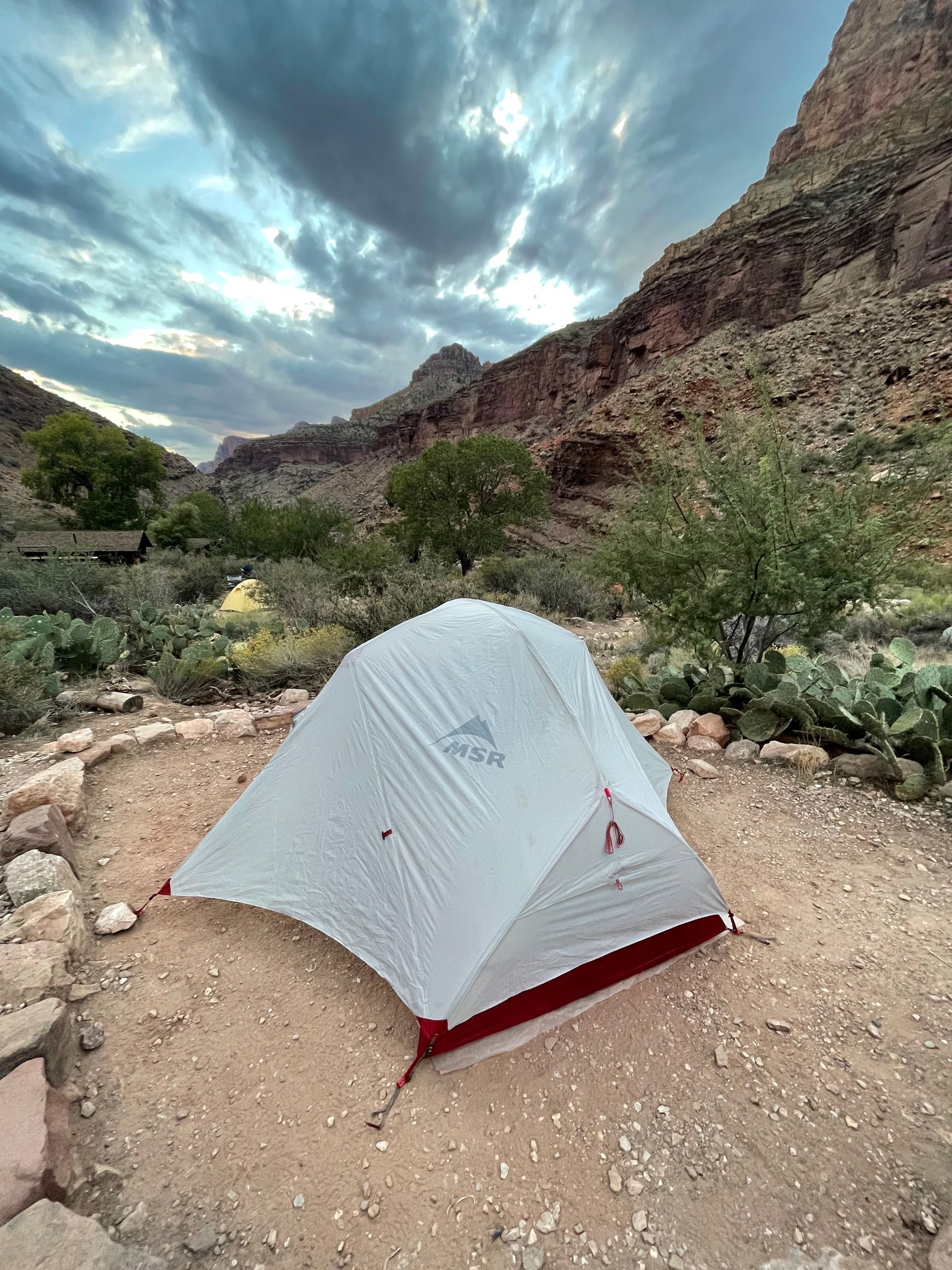 A small white tent is sitting in the middle of a desert.