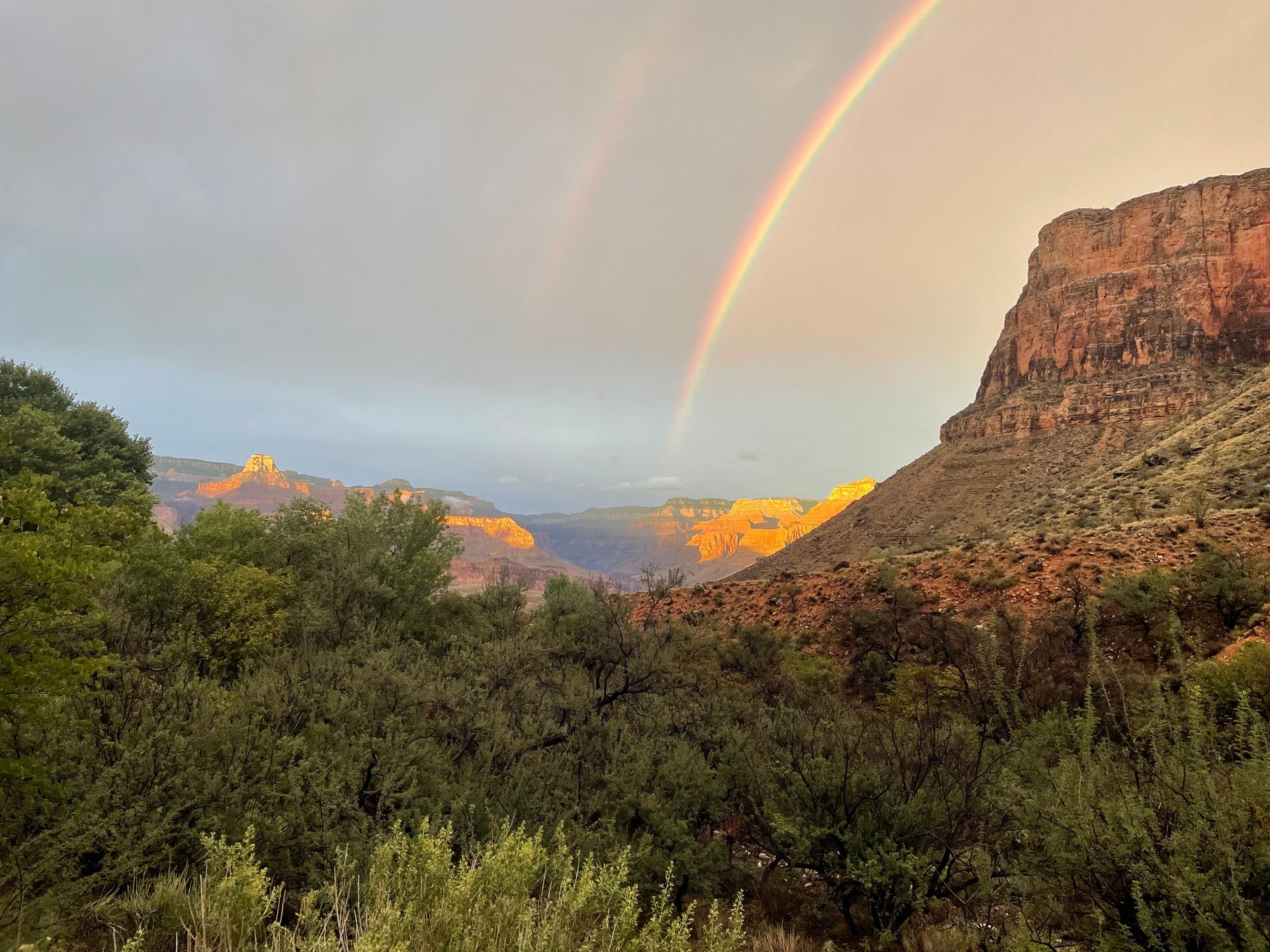 There is a double rainbow in the sky over the grand canyon.