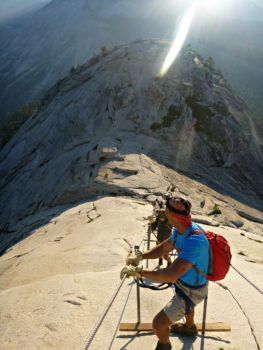 A man with a backpack is standing on top of a mountain.