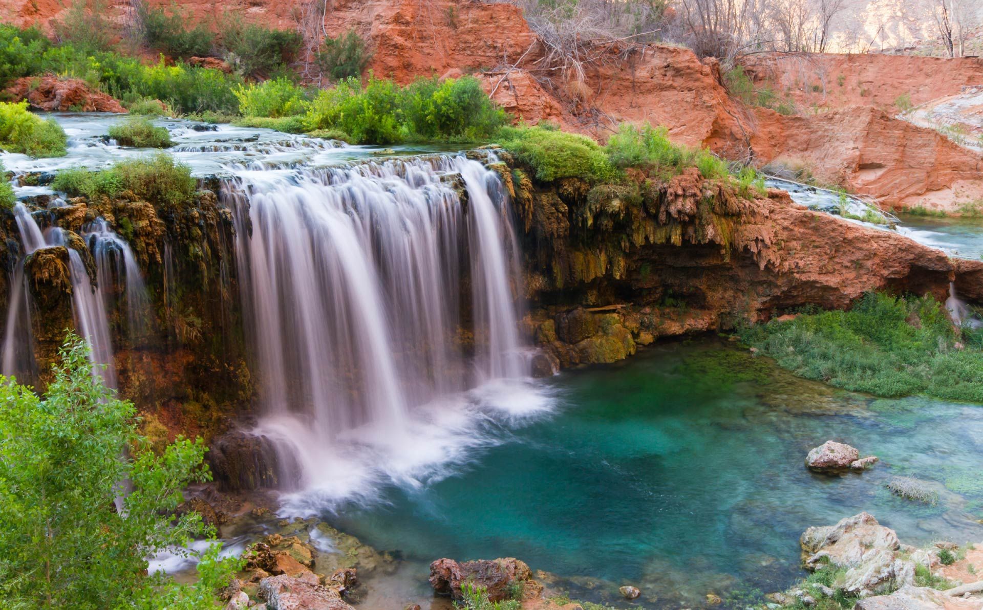 There is a waterfall in the middle of a river surrounded by trees.