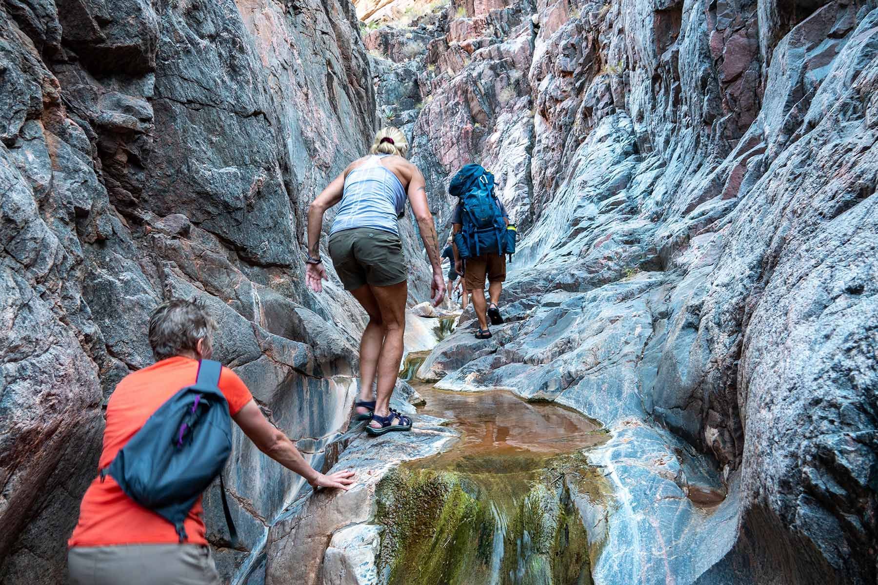 A man and a woman are hiking through a canyon.