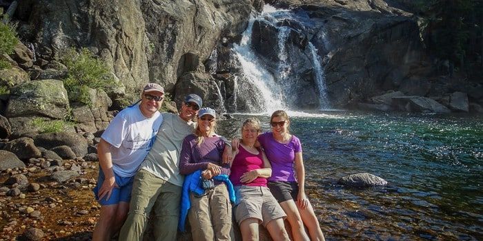 A group of people are posing for a picture in front of a waterfall.