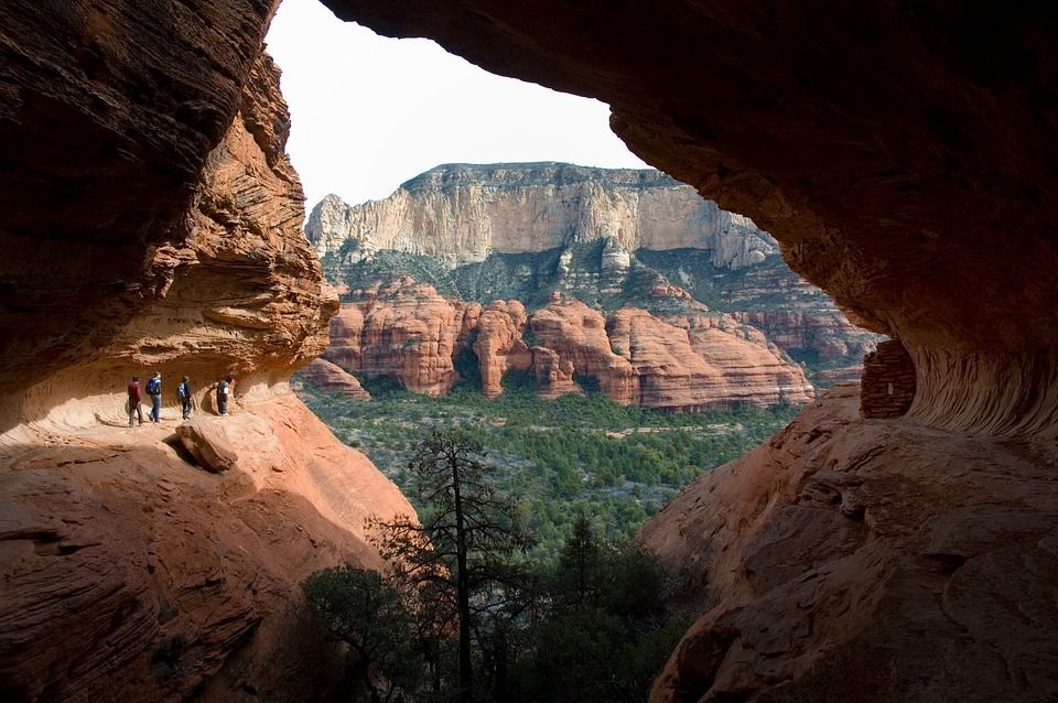 A group of people are standing in a cave overlooking a canyon.