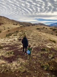 A man and a child are walking up a hill.