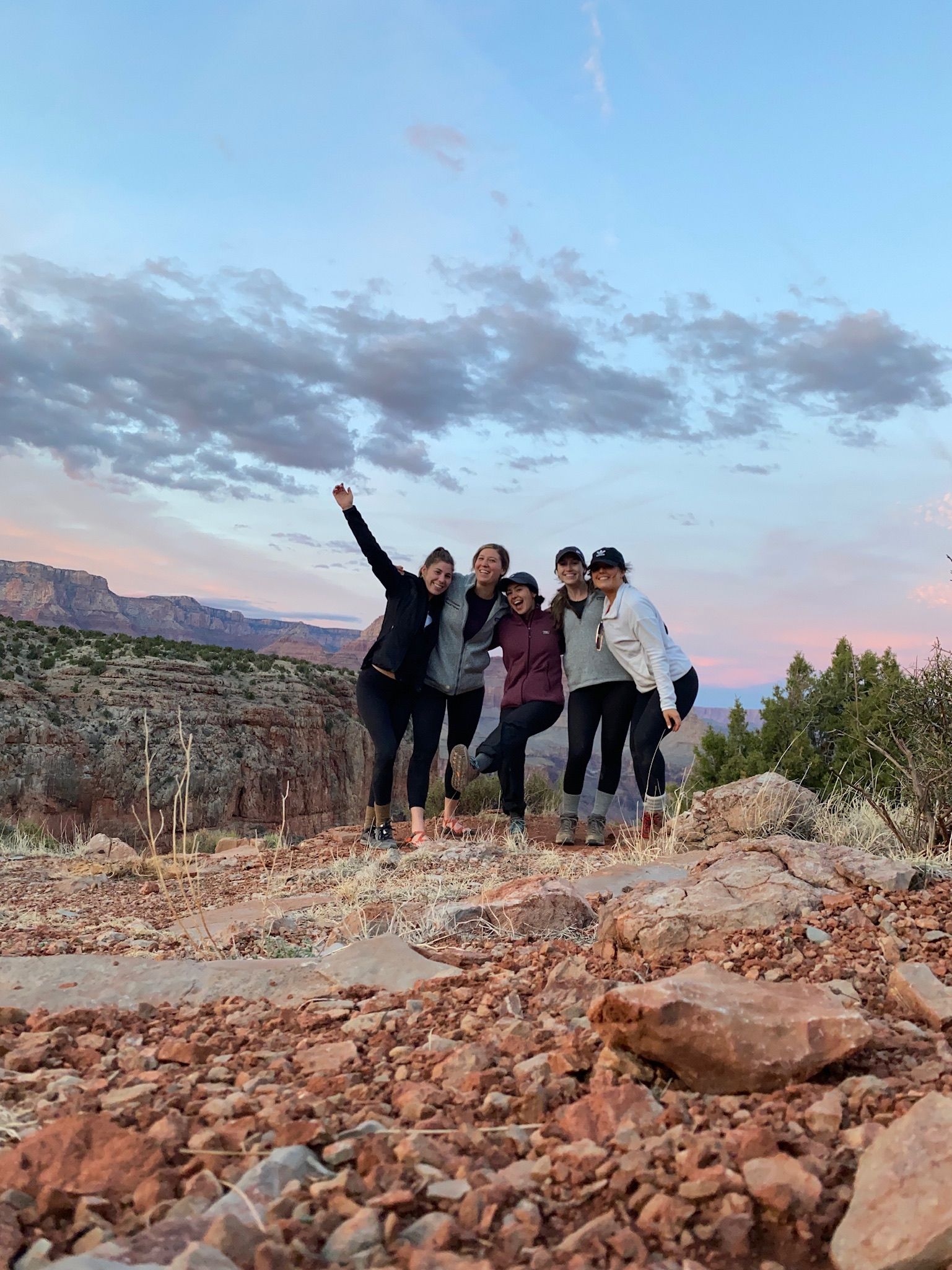 A group of people are posing for a picture on top of a rocky hill.