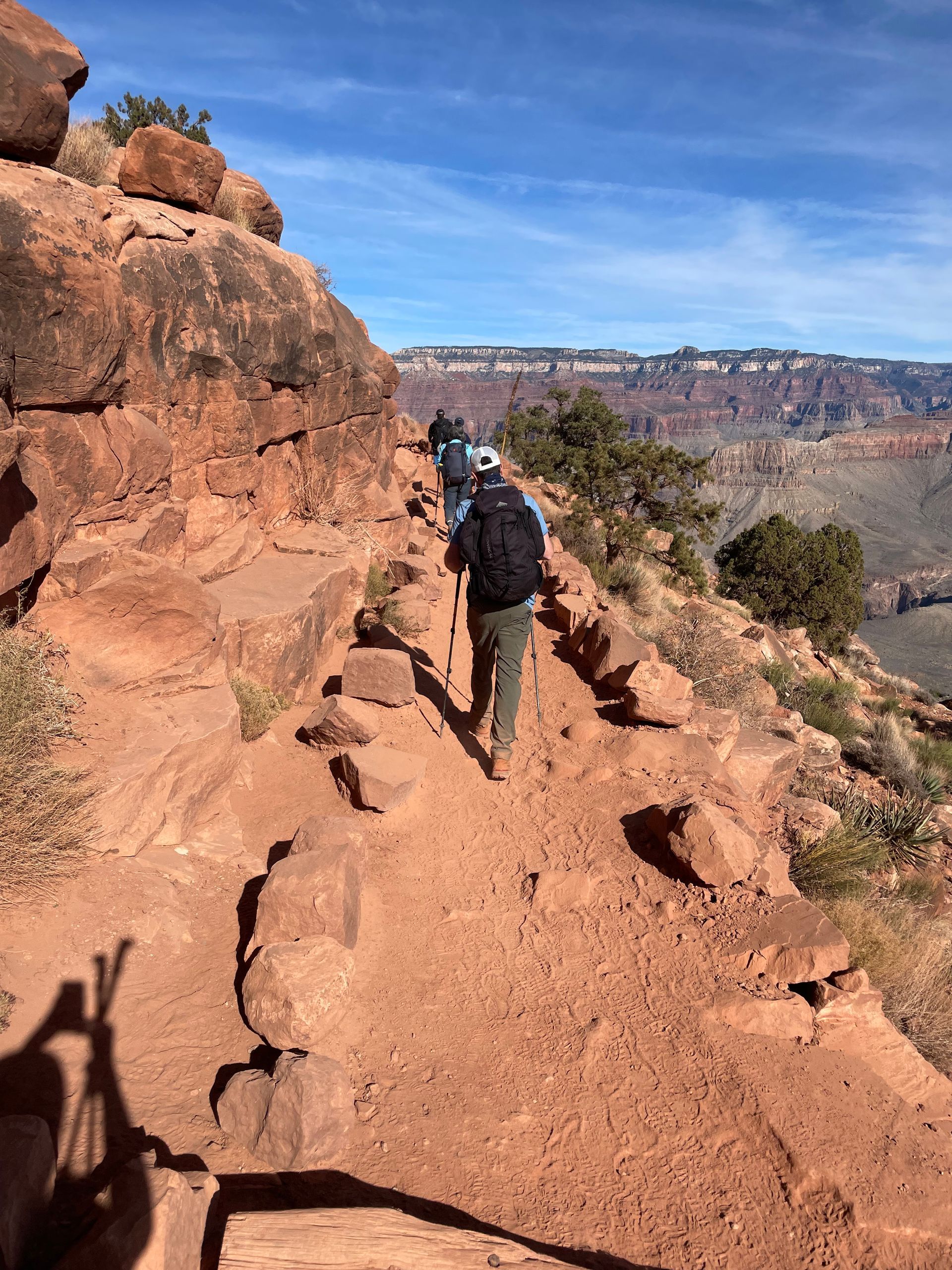 A group of people are walking down a dirt trail.