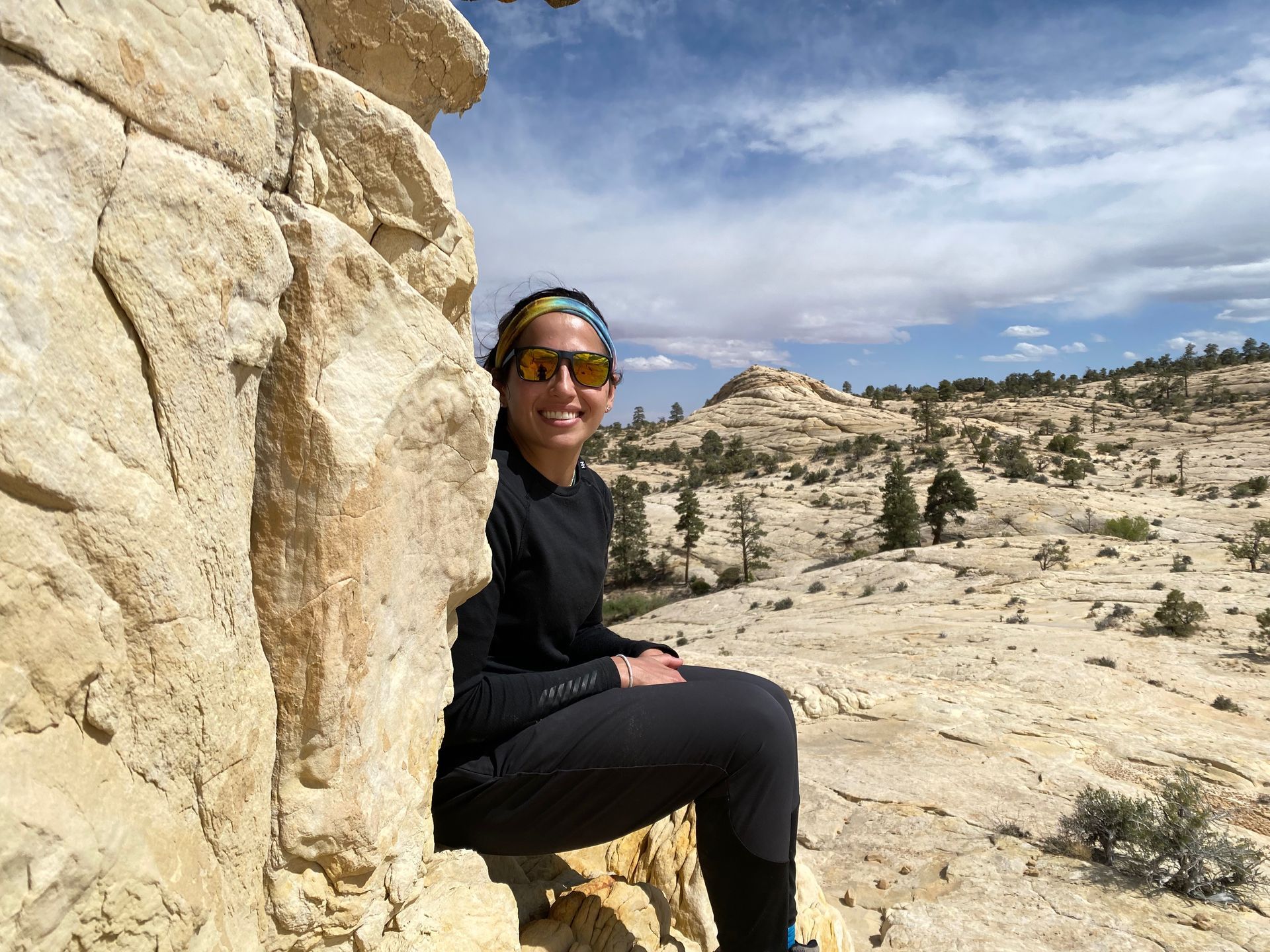 A woman is sitting on a rock in the desert.