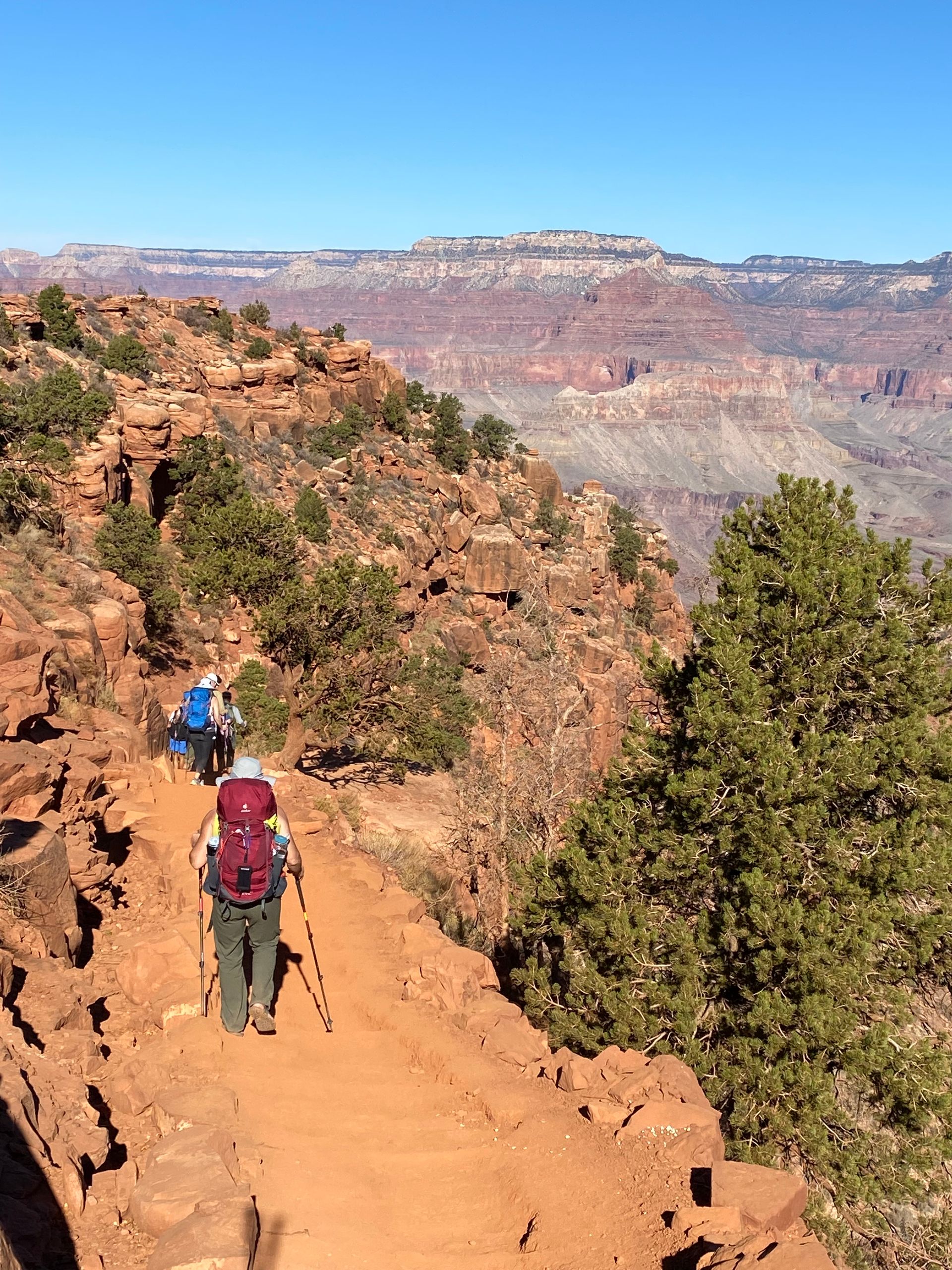 Two people are hiking up a dirt trail on a mountain.
