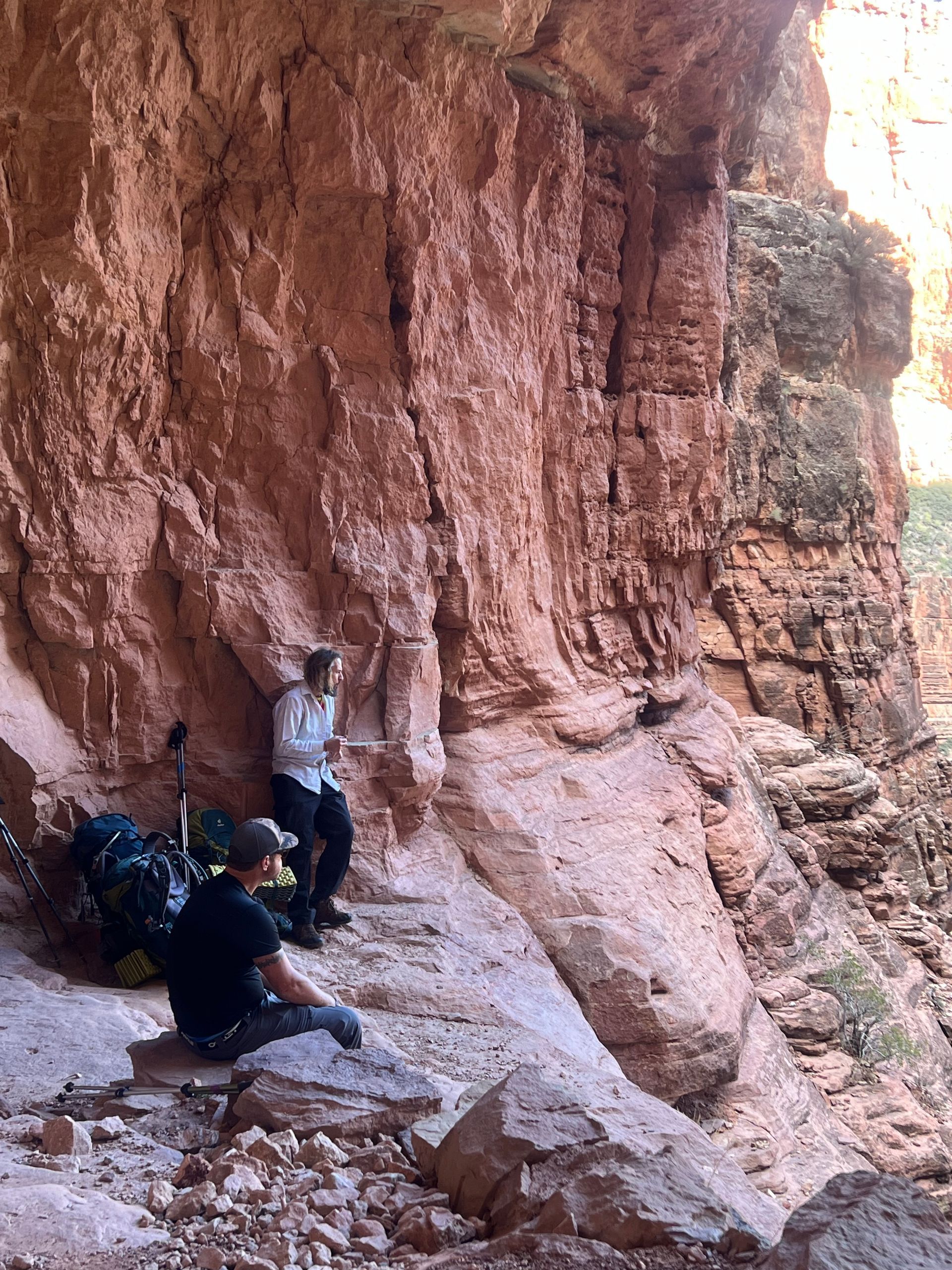 Two people are sitting on a rock near a cliff.