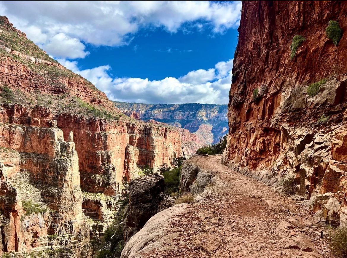 A dirt road going through a canyon with mountains in the background.