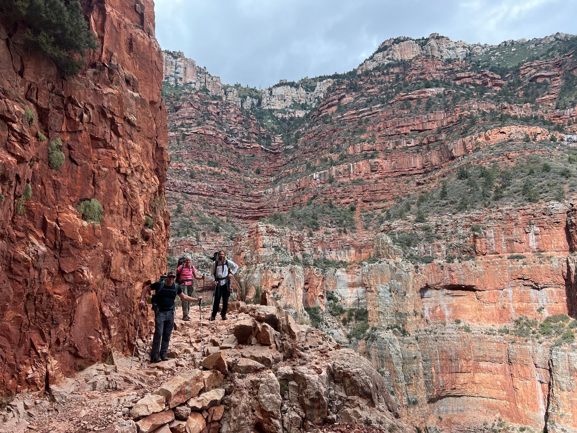 A group of people are standing on a rocky trail in the mountains.