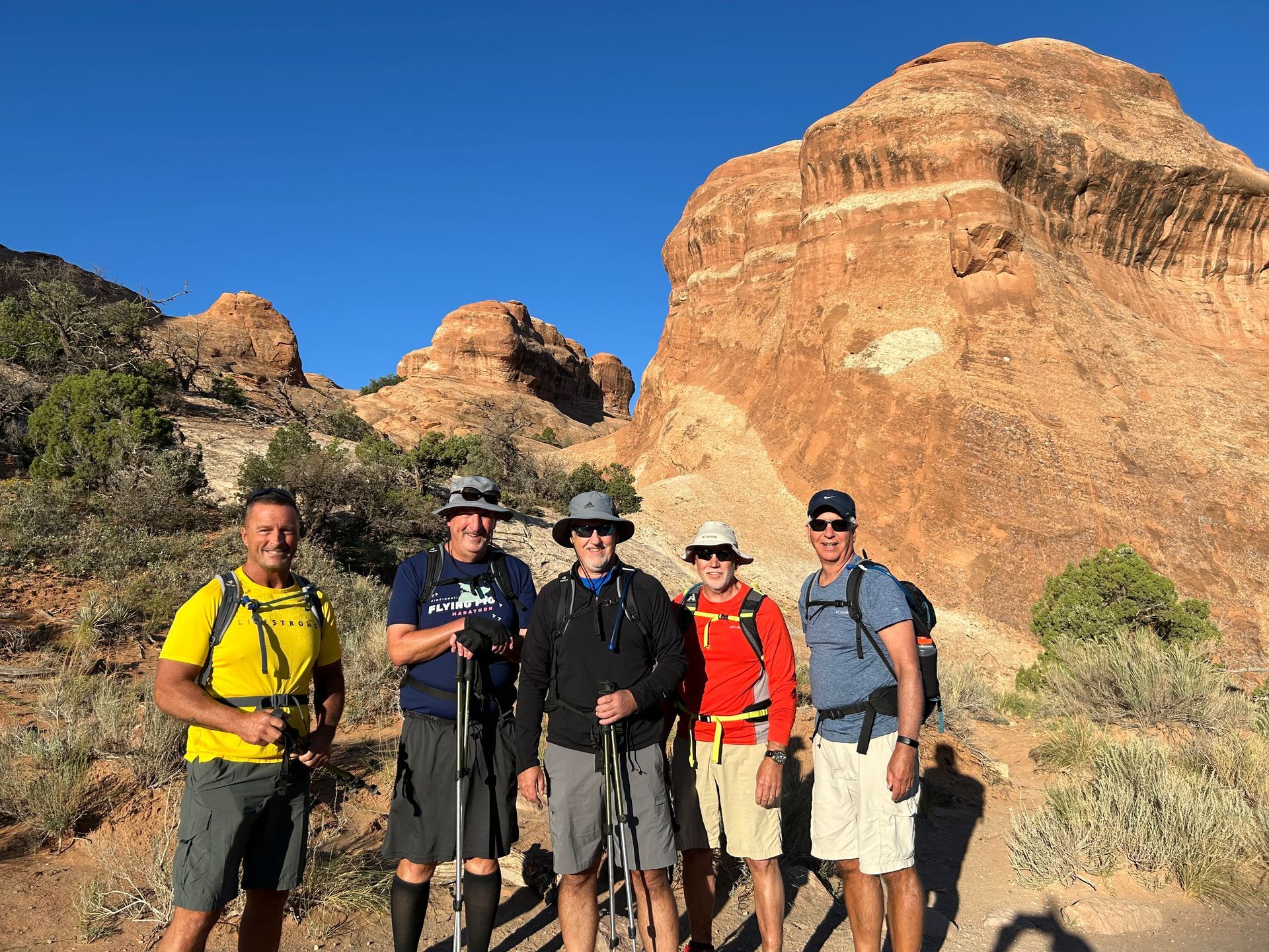 A group of men are standing next to each other in front of a mountain.