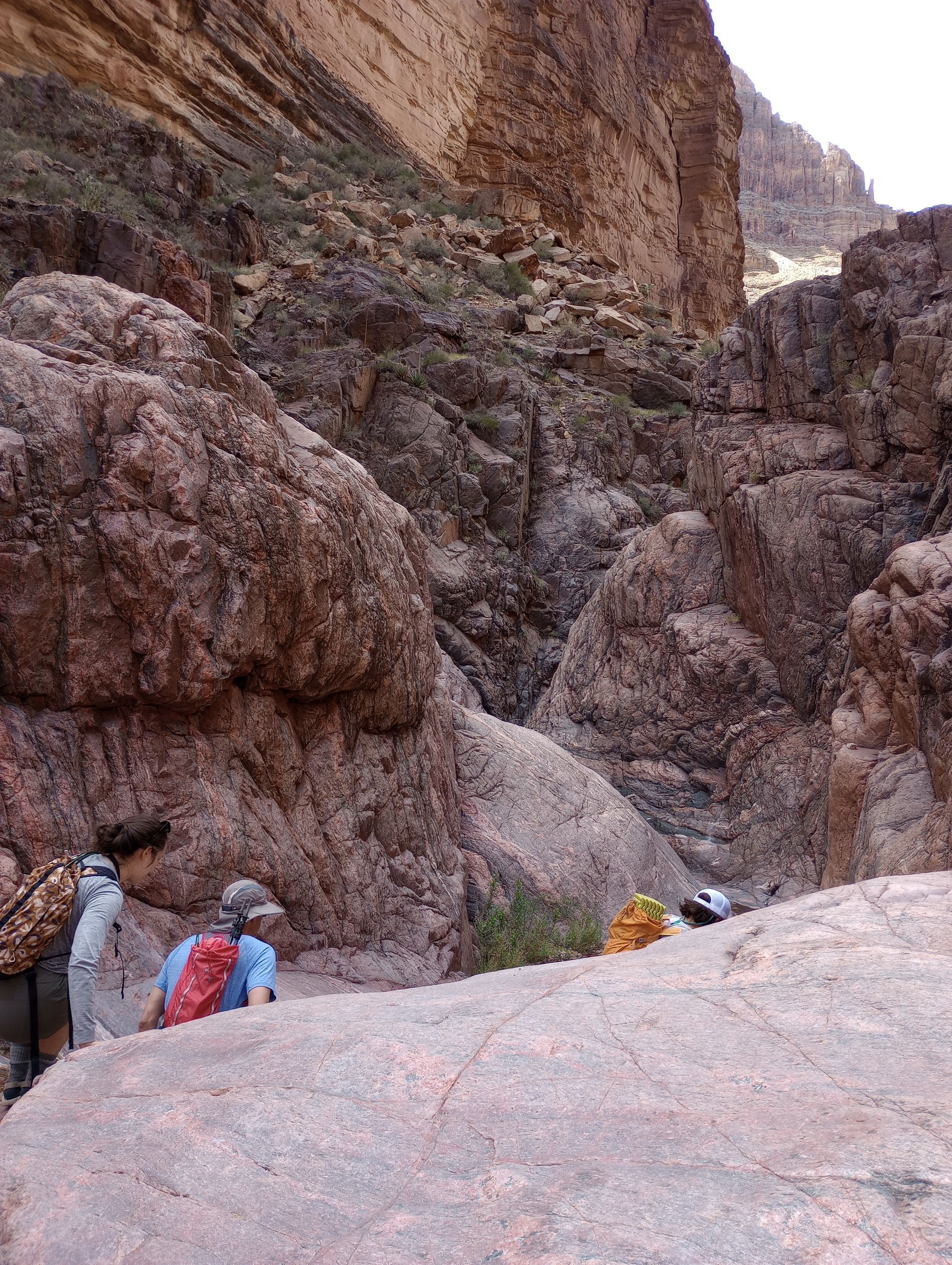 A group of people are walking down a rocky canyon.
