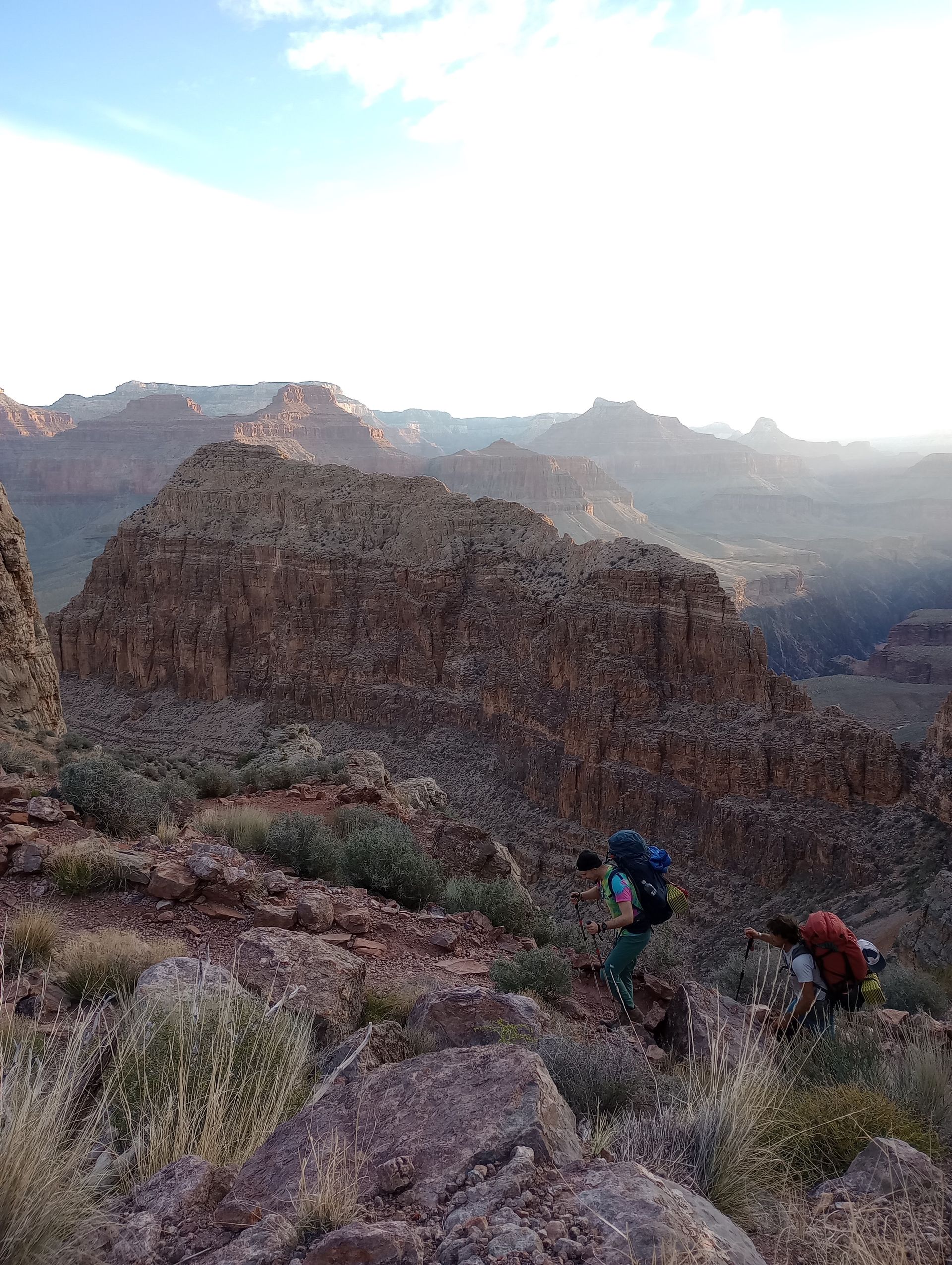 Two people are hiking up a mountain with backpacks.