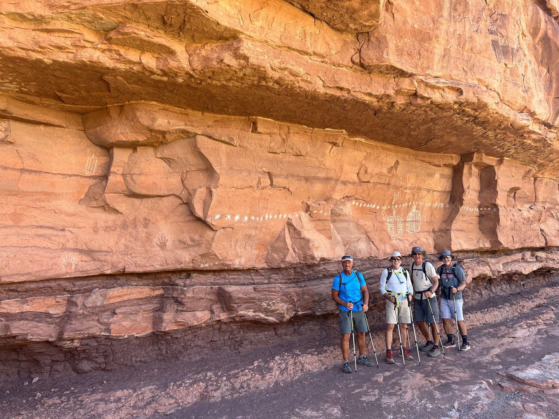 A group of people are standing in front of a large rock wall.