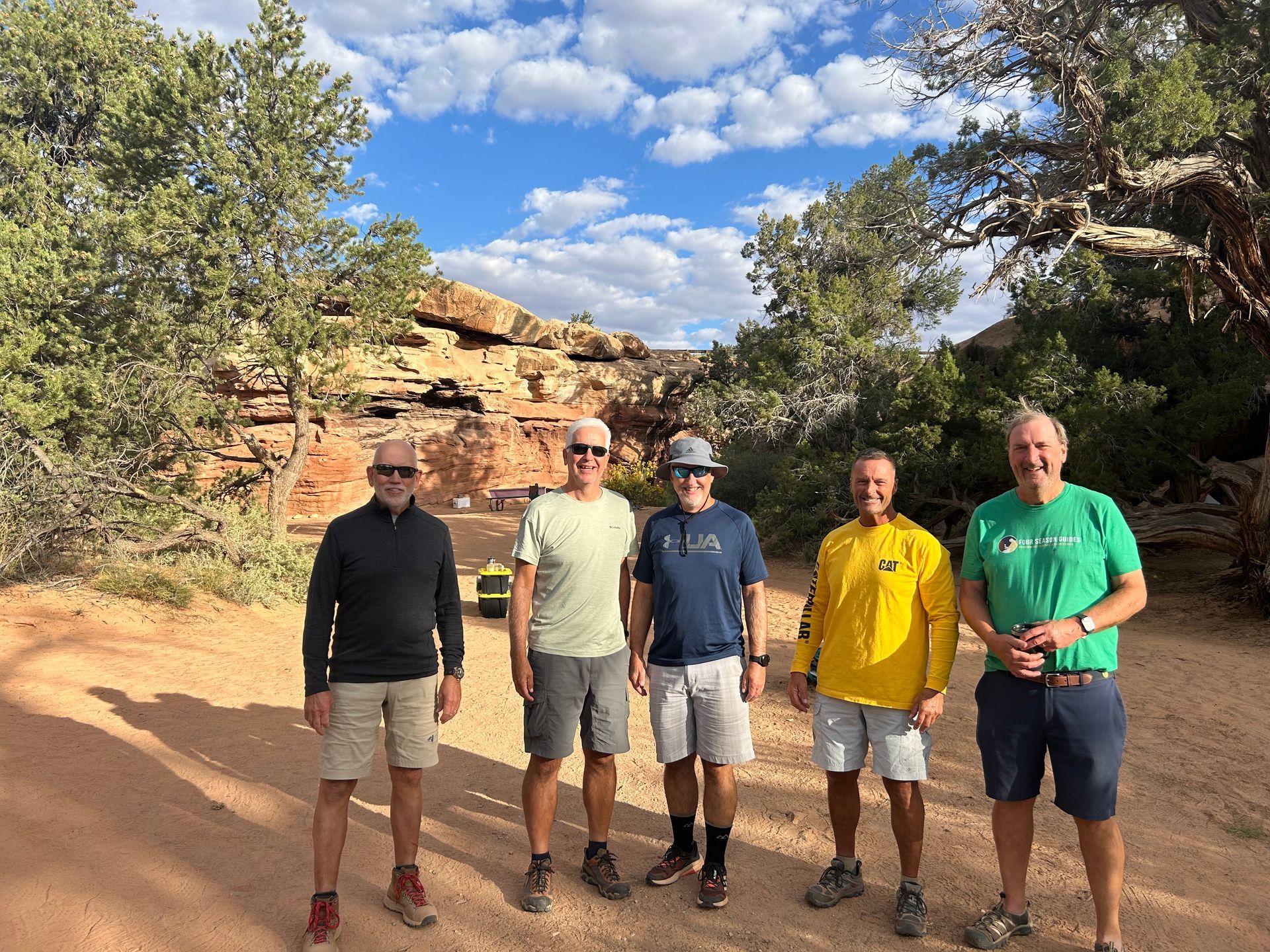 A group of men are standing next to each other on a dirt road.