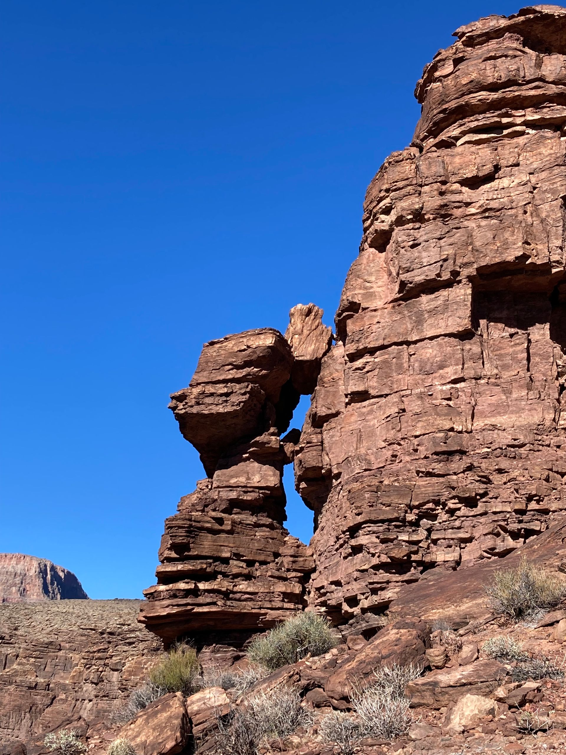 A large rock formation in the desert with a blue sky in the background