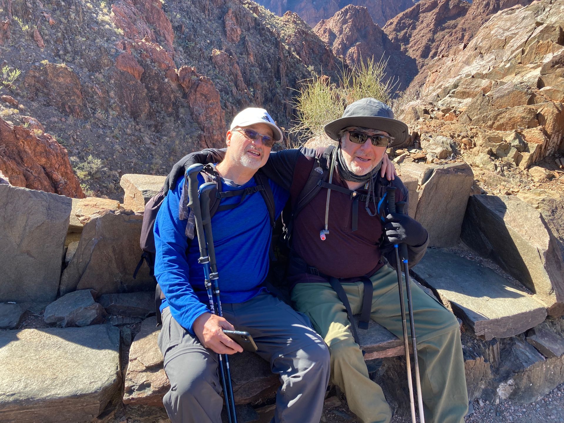 Two men are sitting next to each other on a rock.