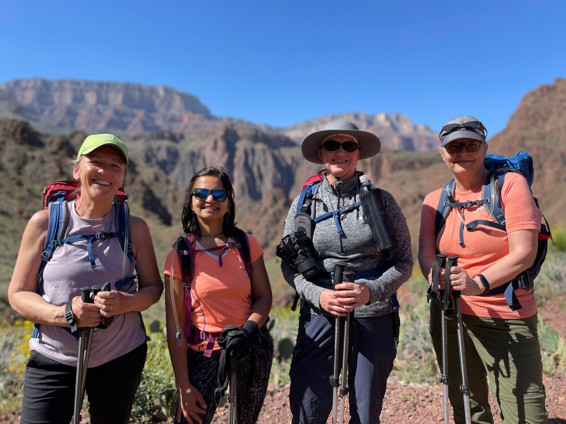 A group of women are standing next to each other in front of a mountain.