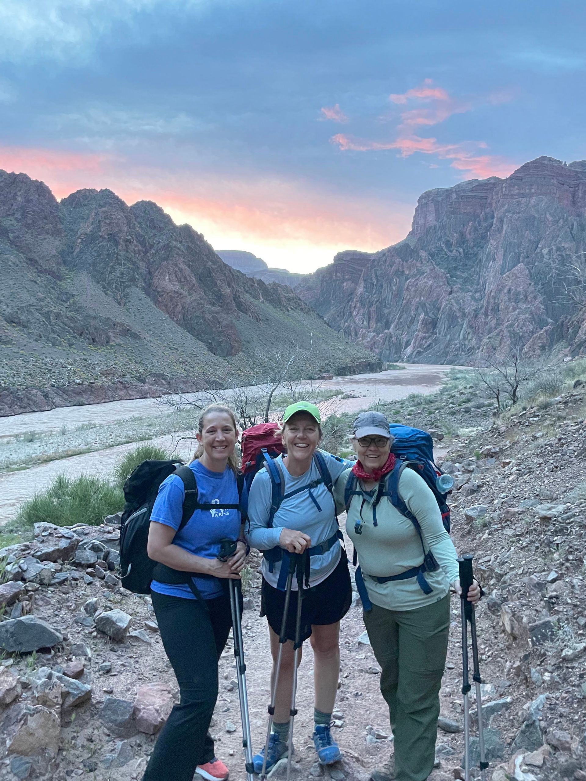 Three women are hiking in the mountains and posing for a picture.