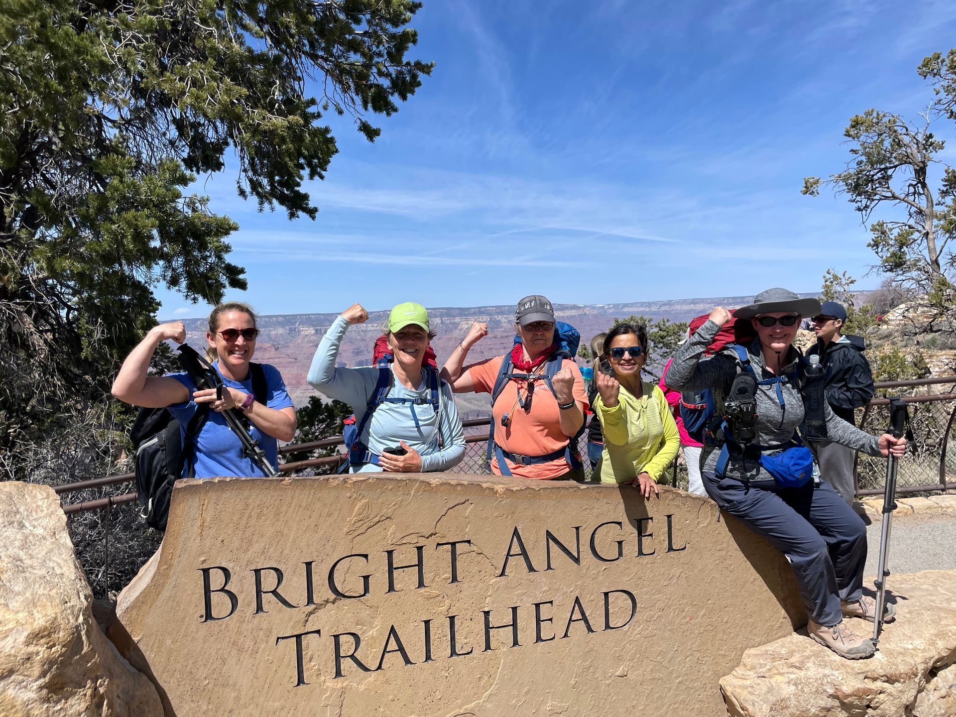 A group of people standing next to a sign that says bright angel trailhead.