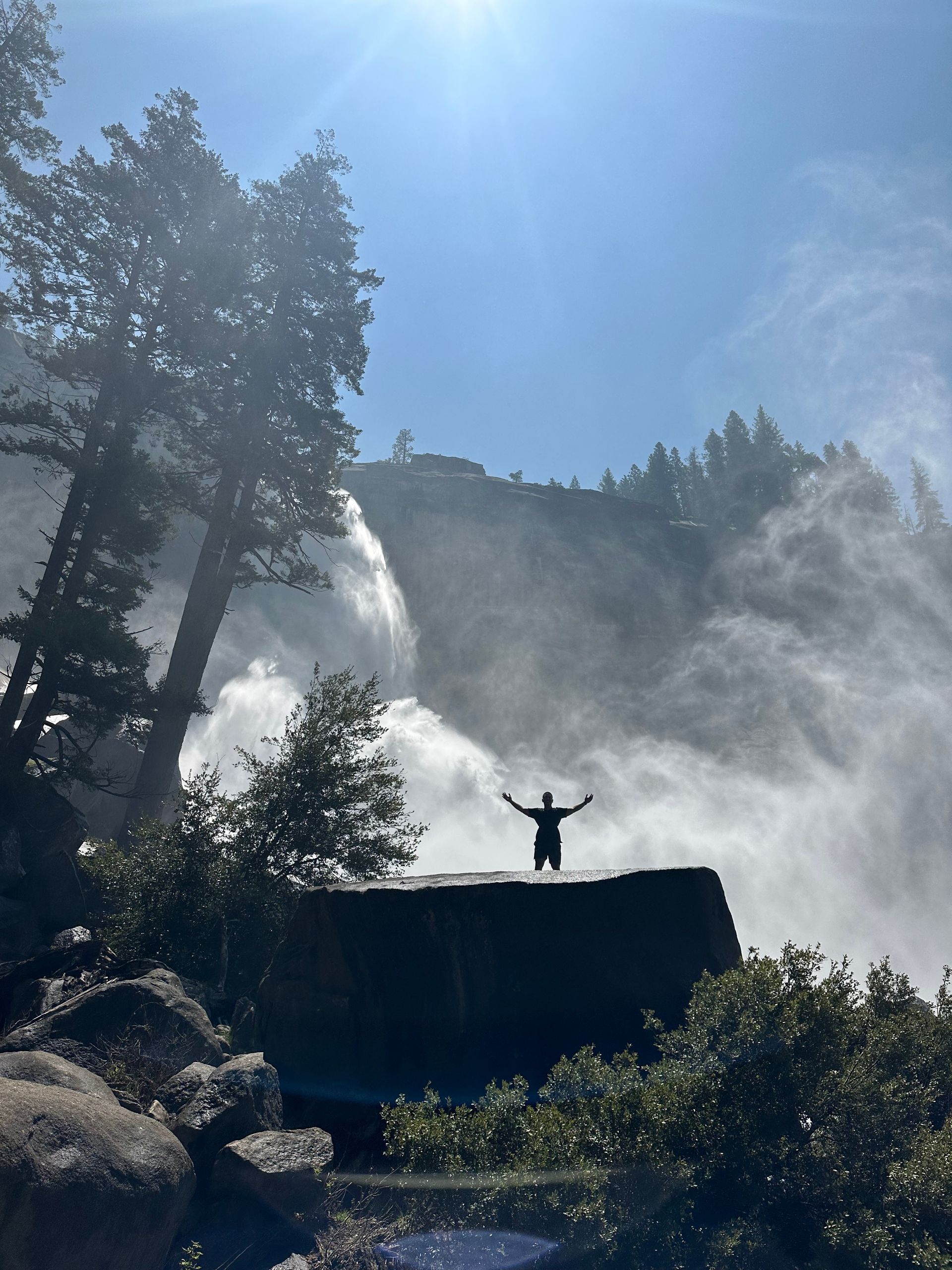 A person standing on top of a waterfall with their arms outstretched