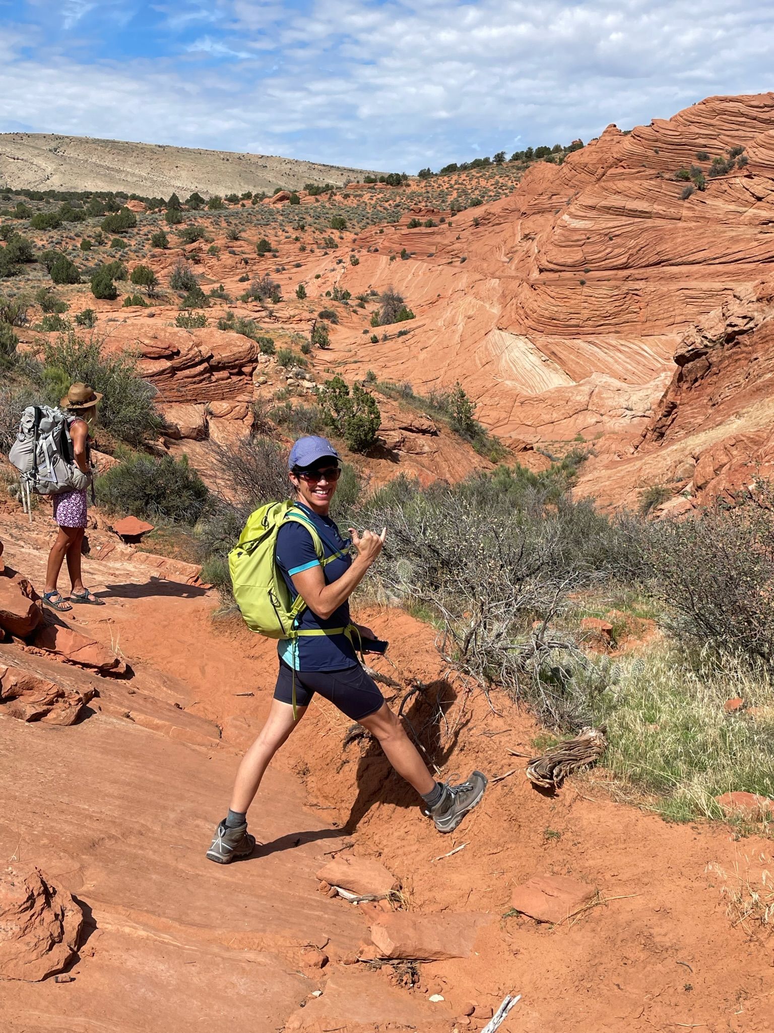 A man with a backpack is walking down a dirt path in the desert.