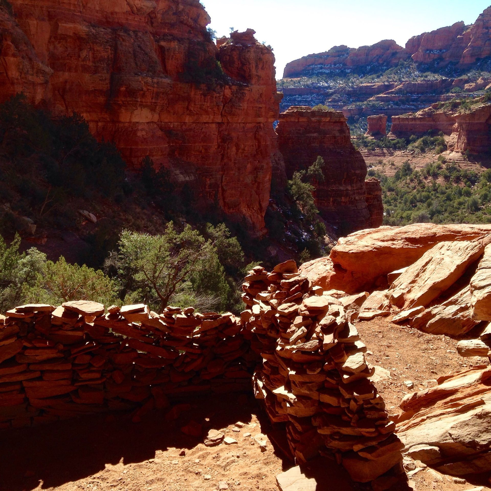 A view of a canyon with a stone wall in the foreground