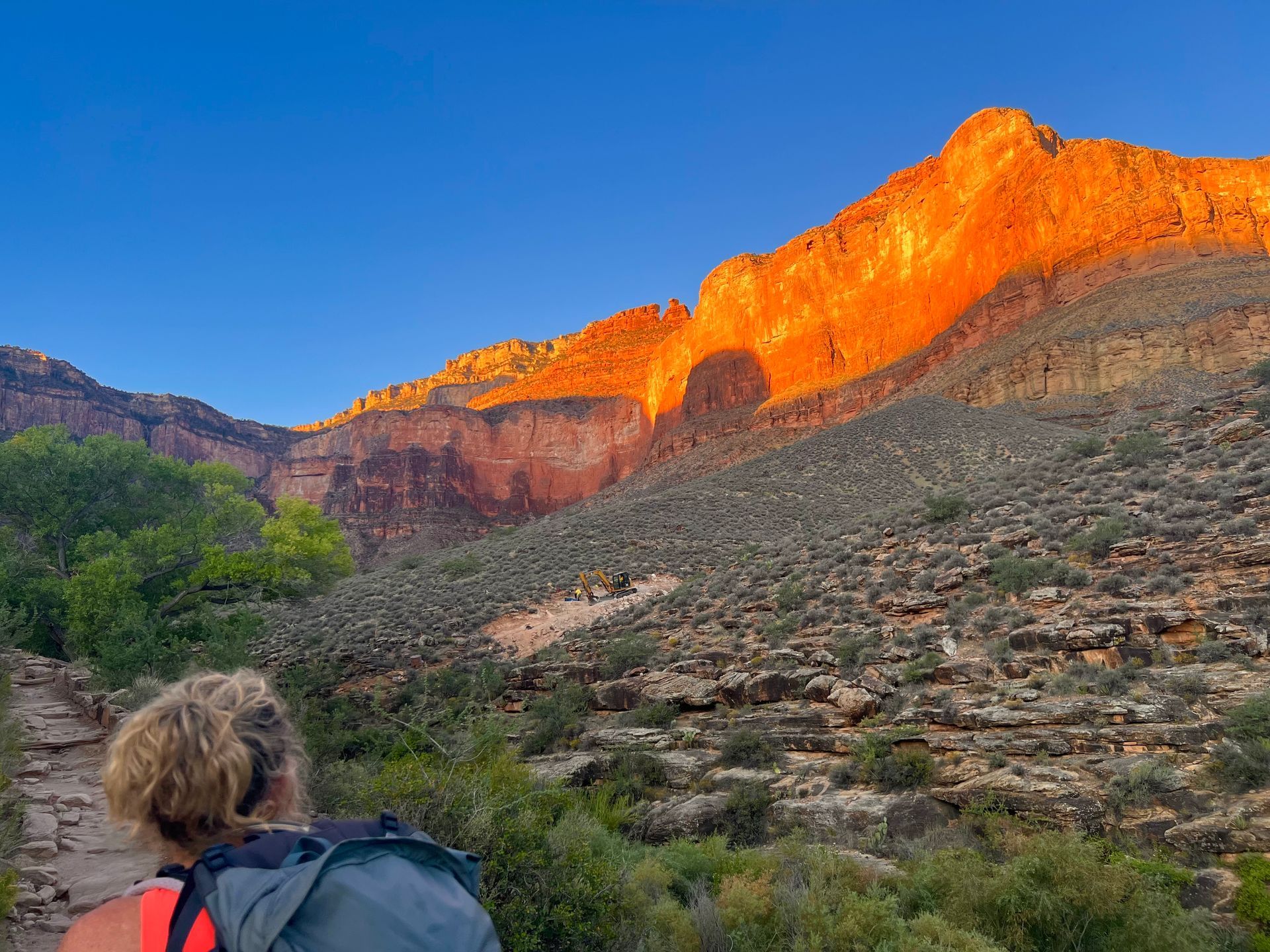 A woman with a backpack is looking at a mountain.