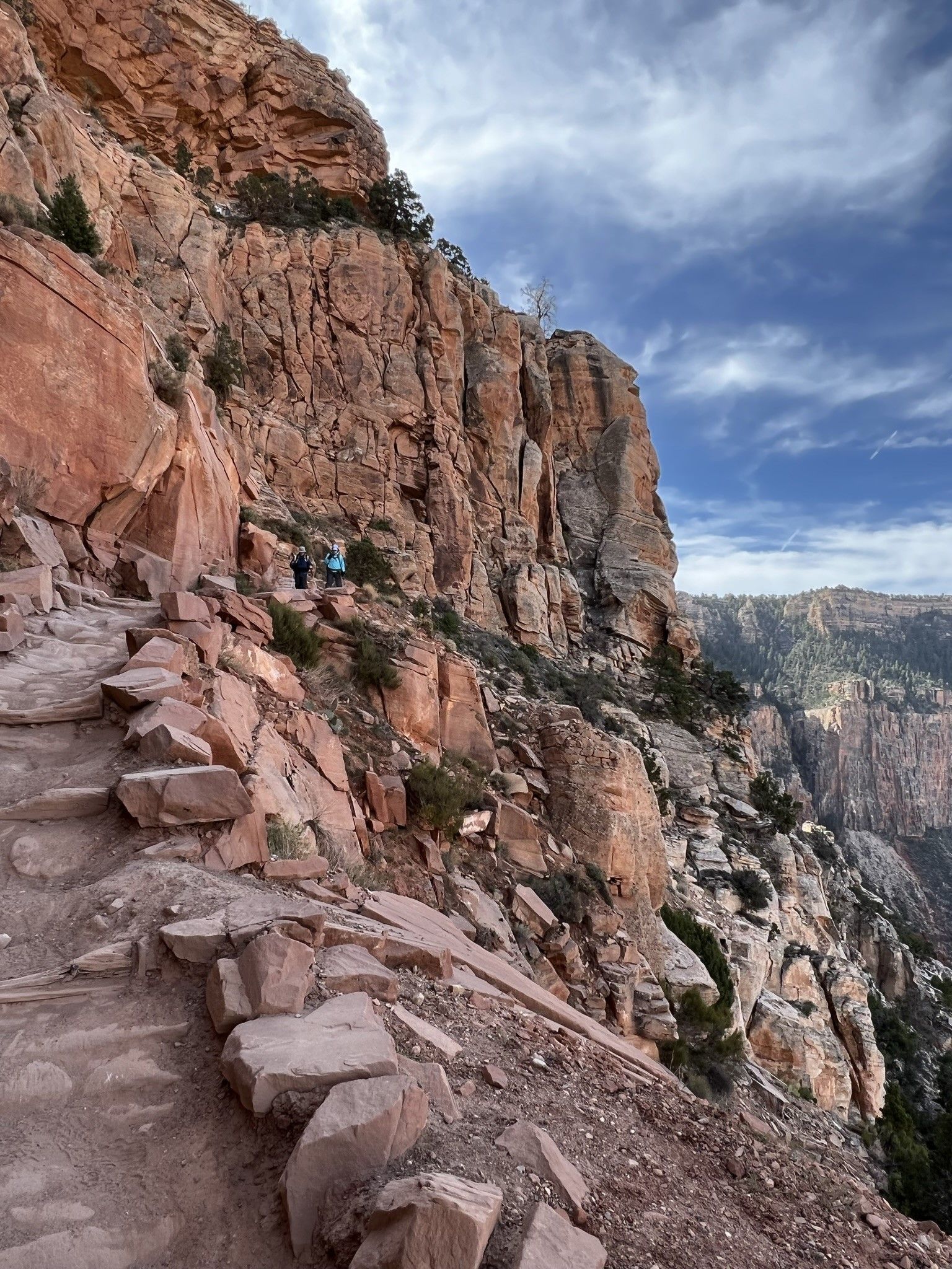 A person is walking down a rocky trail on a mountain.