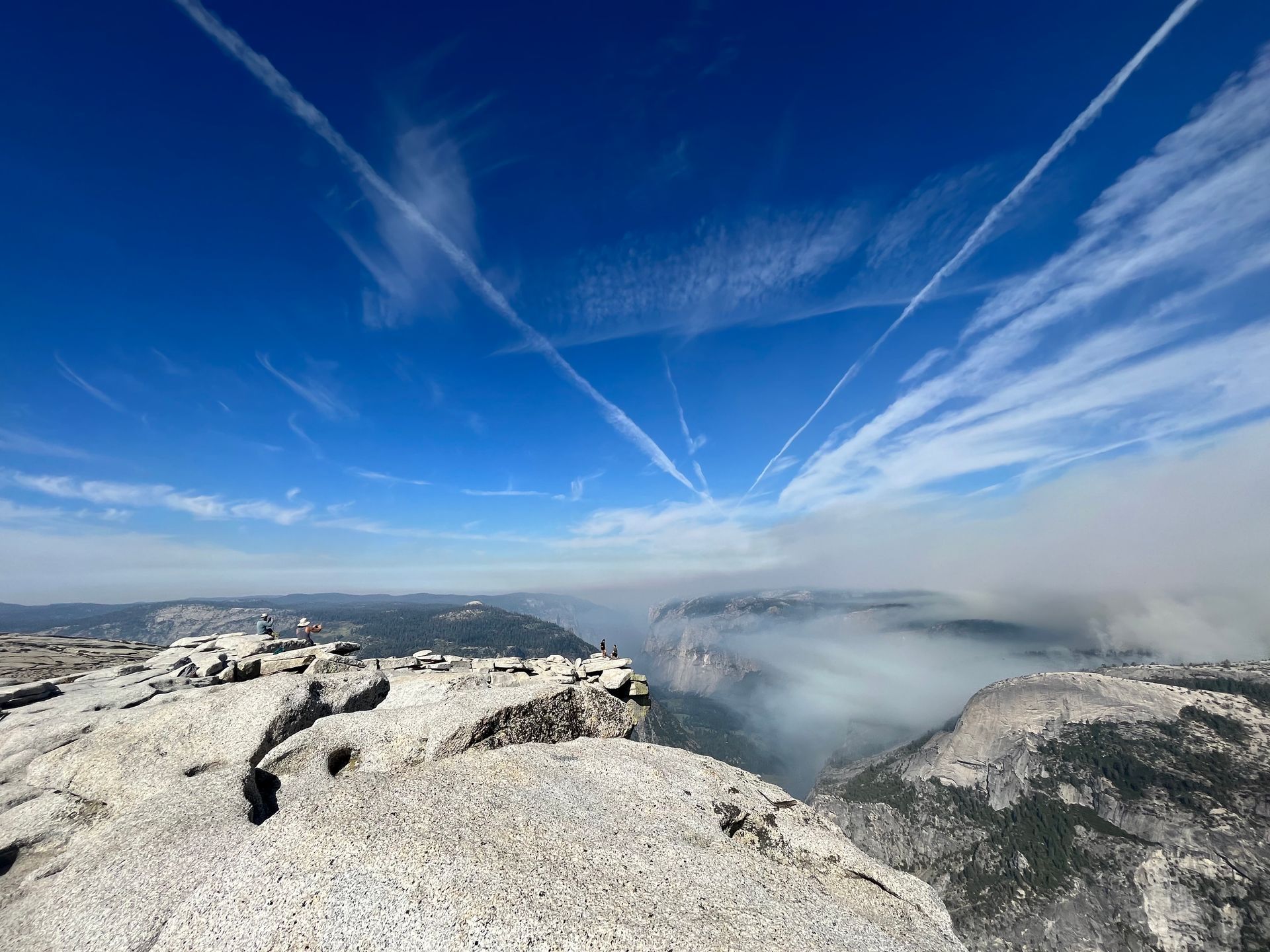 A view from the top of a mountain with a blue sky and clouds