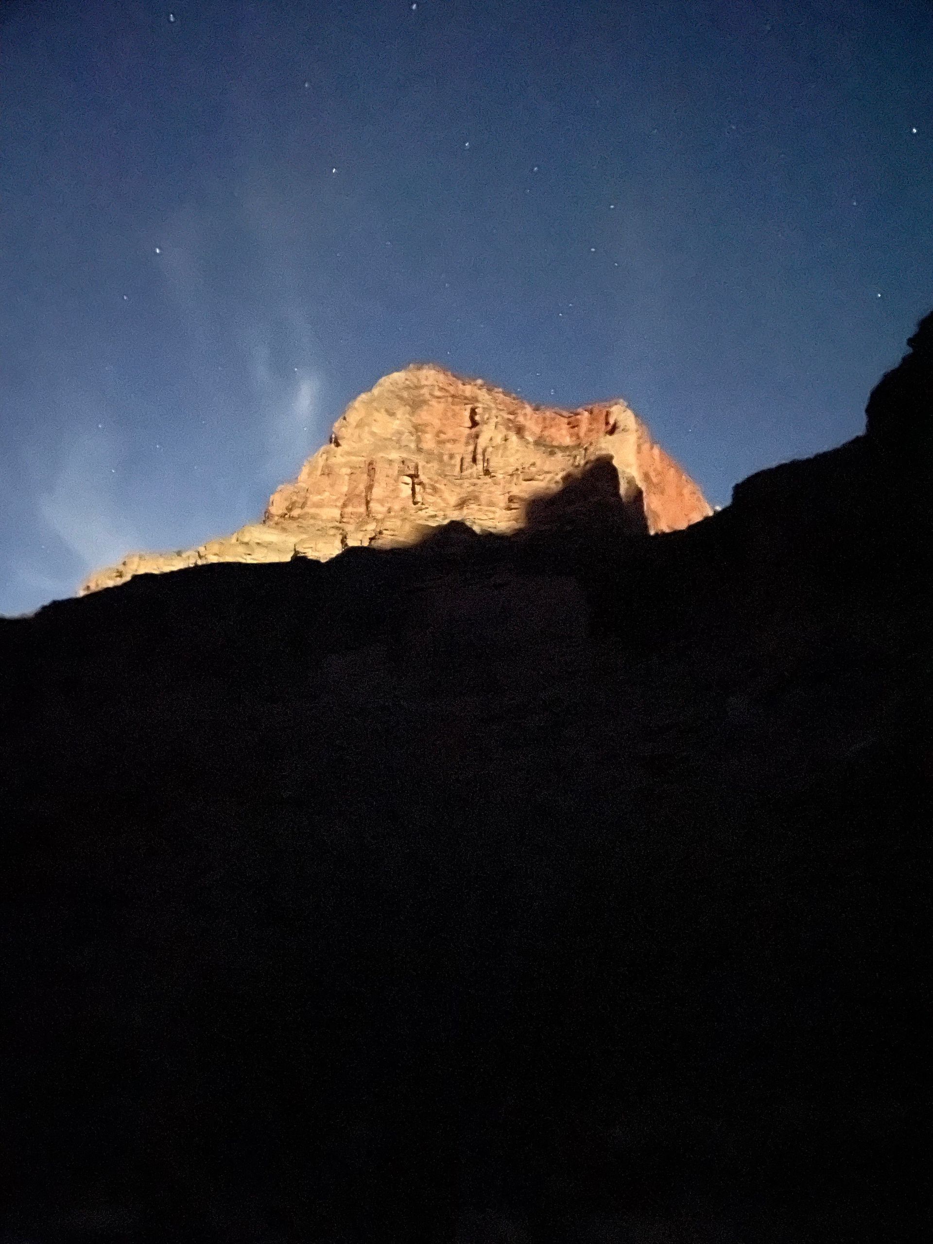 A mountain with a blue sky and stars in the background