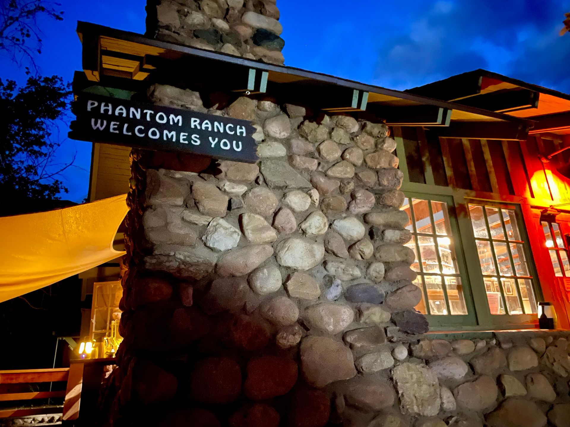 A sign on a stone wall says phantom ranch welcomes you.