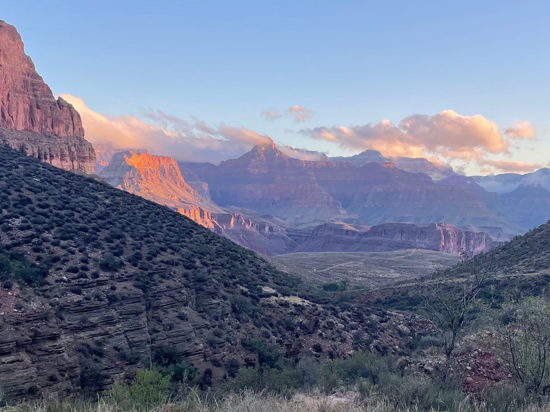 A view of a valley with mountains in the background at sunset.