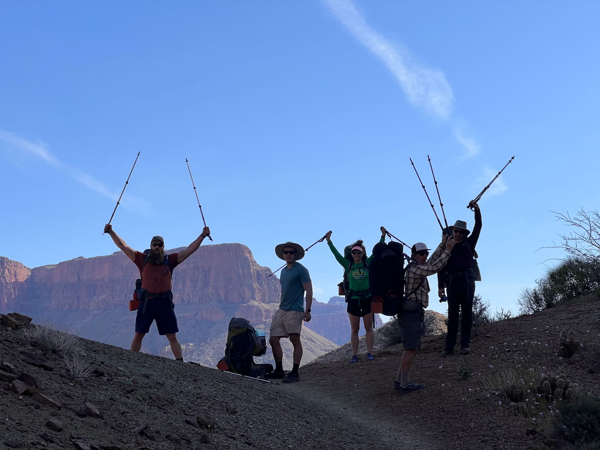 A group of people standing on top of a hill with their arms in the air
