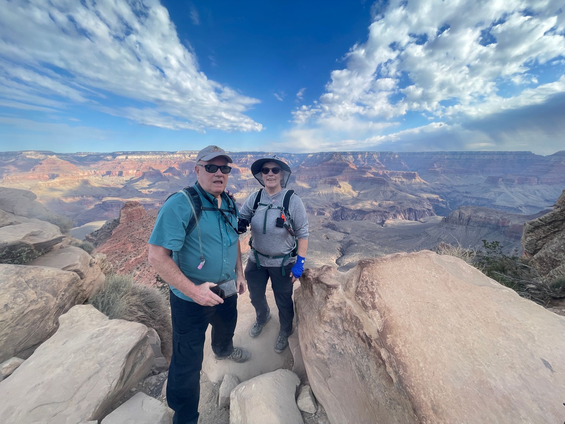 Two men are standing on top of a rocky cliff overlooking a canyon.