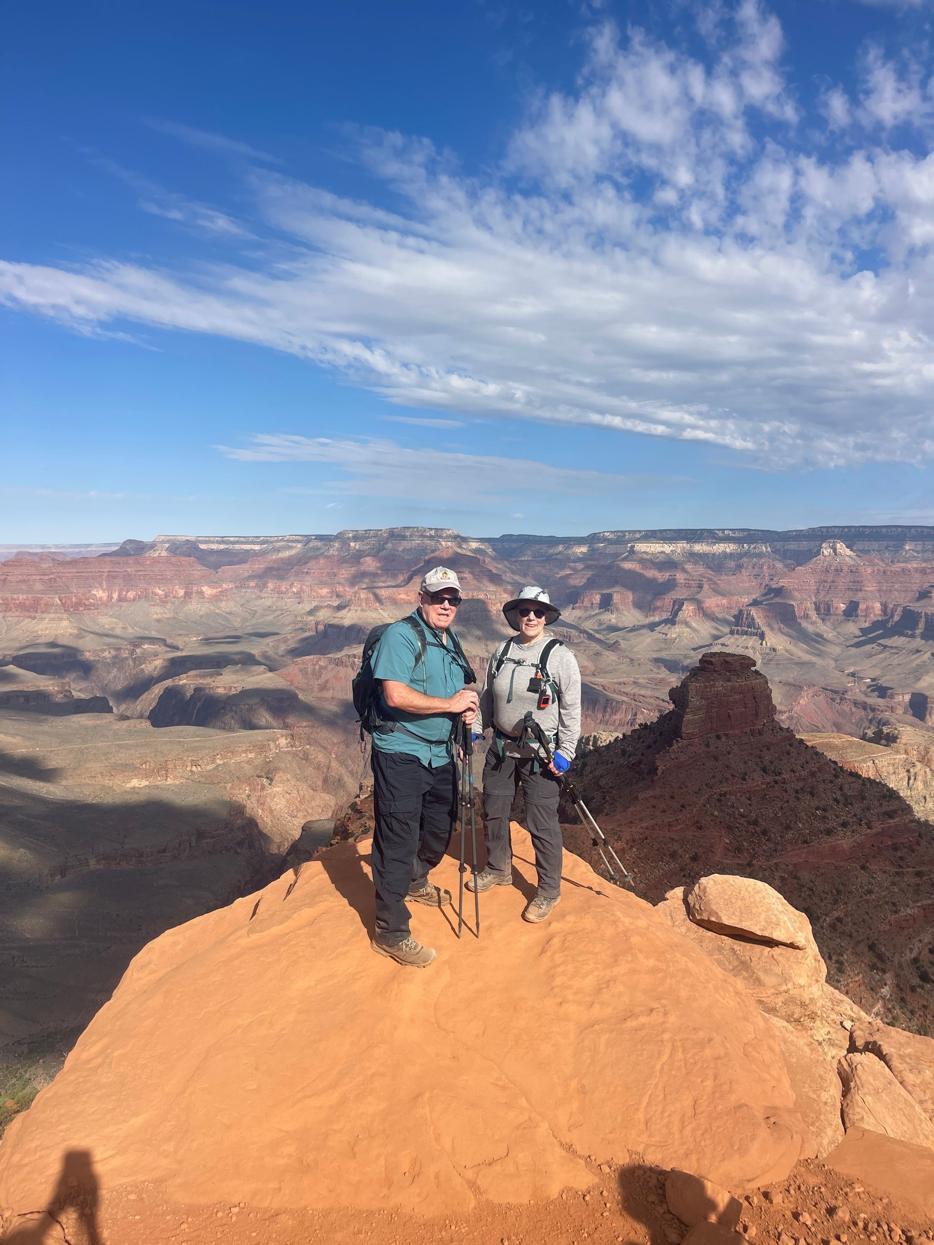 A man and a woman are standing on top of a mountain.