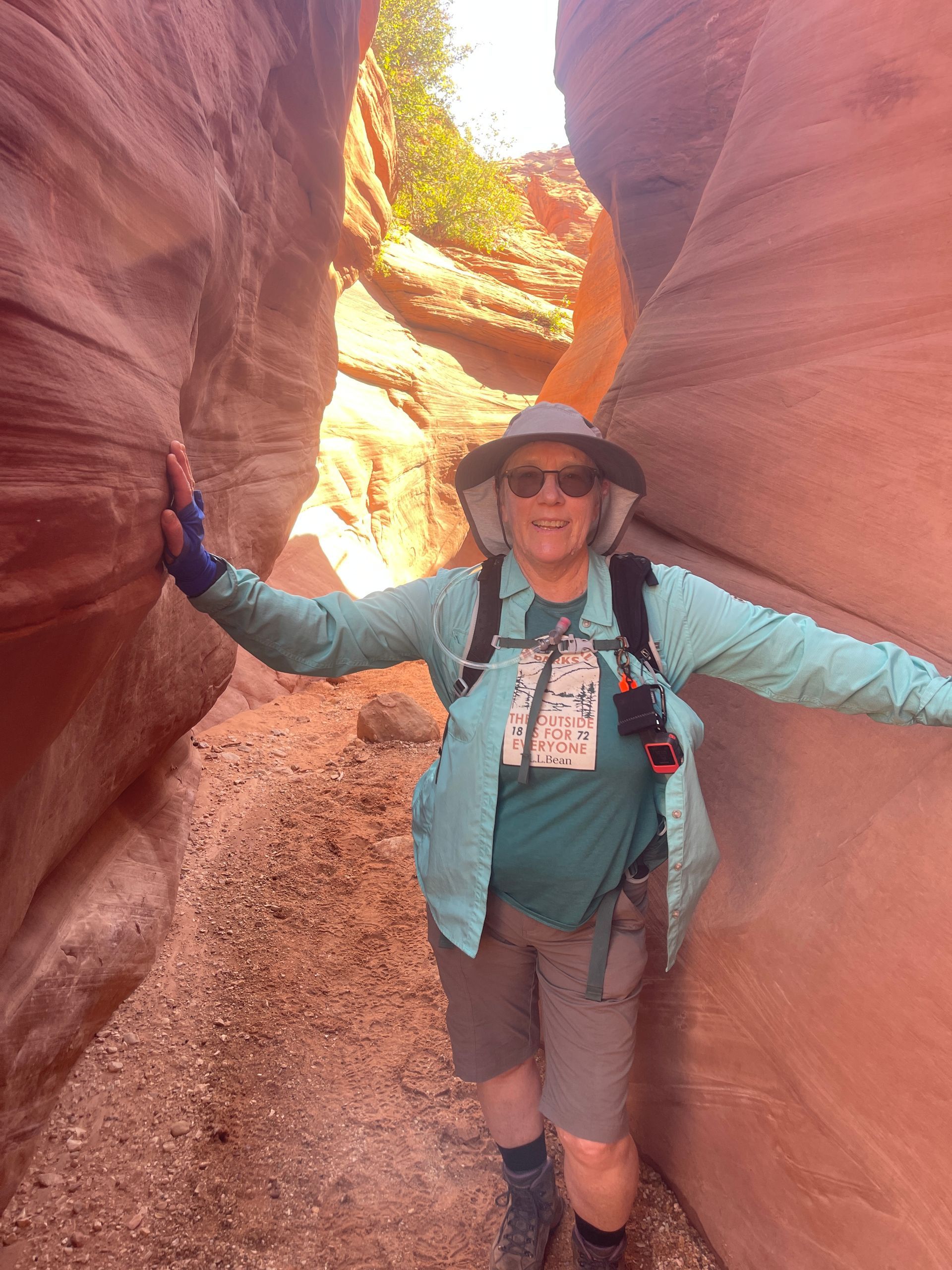 A woman is standing in a canyon with her arms outstretched.