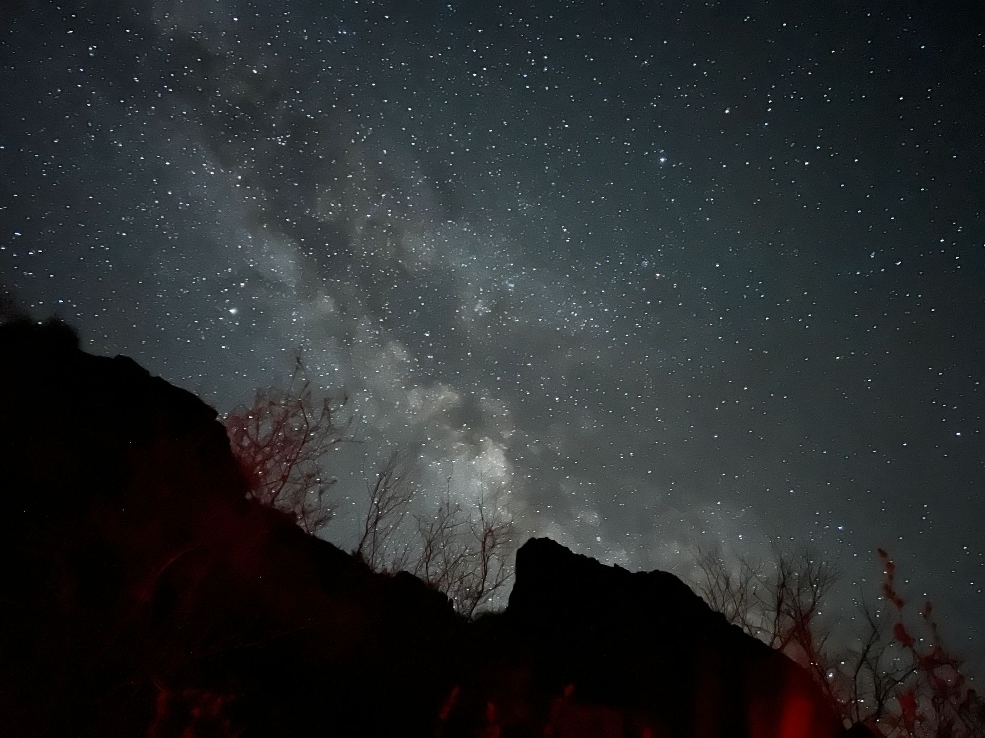 A starry night sky with a mountain in the foreground